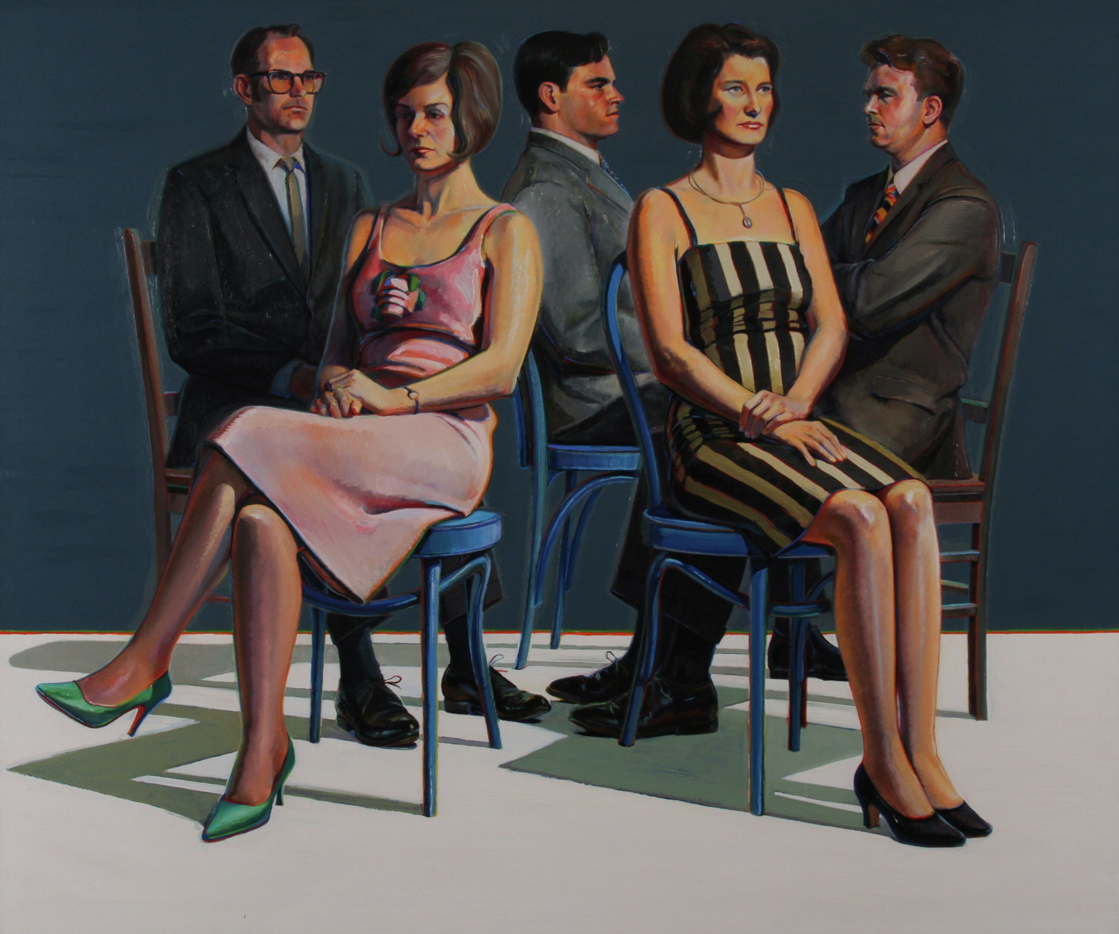 Five people sit in a row of chairs facing the same direction. Two women wear dresses, while three men wear suits. The background is a plain, dark blue.