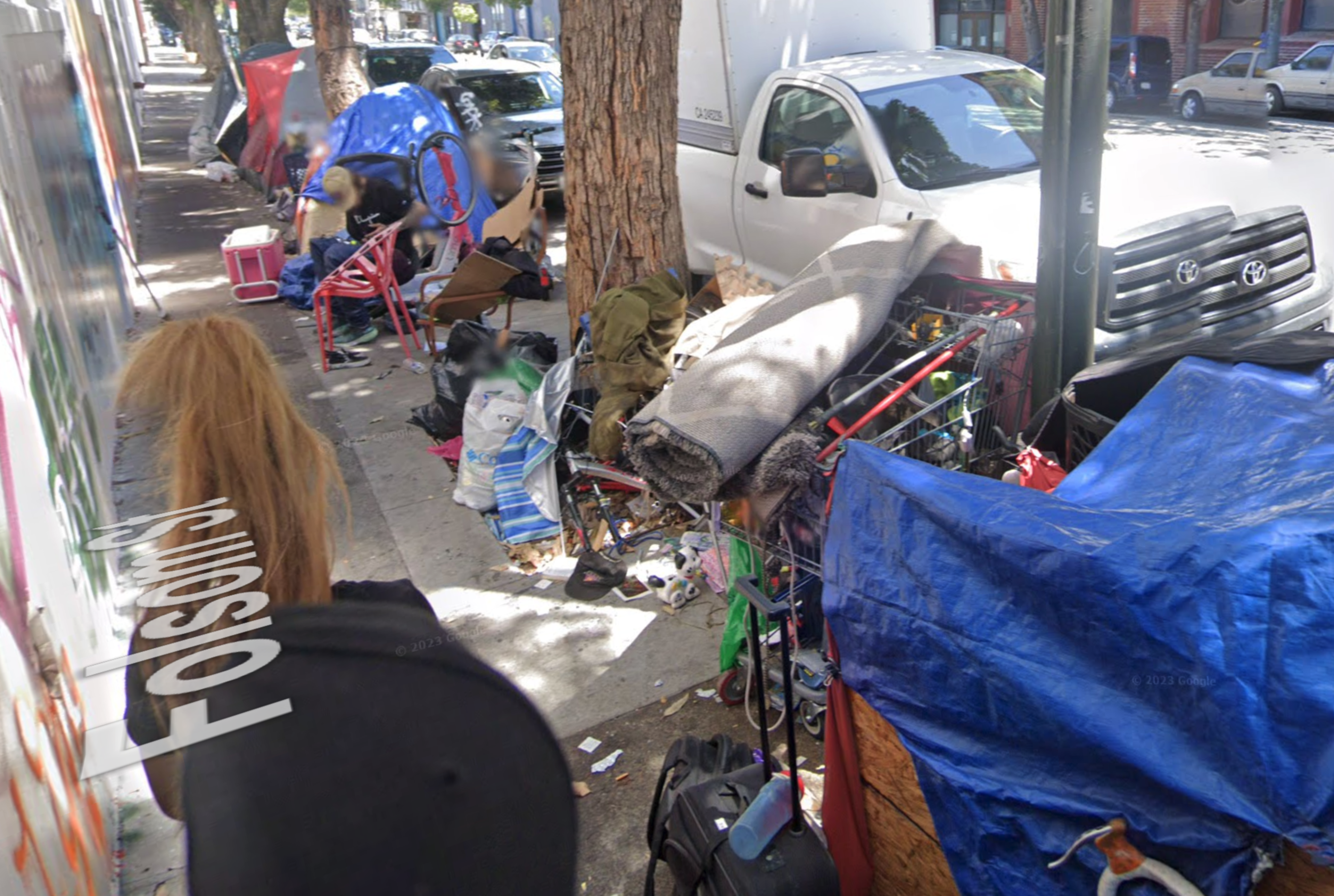 Unhoused people camp on a sidewalk outside a grocery store.