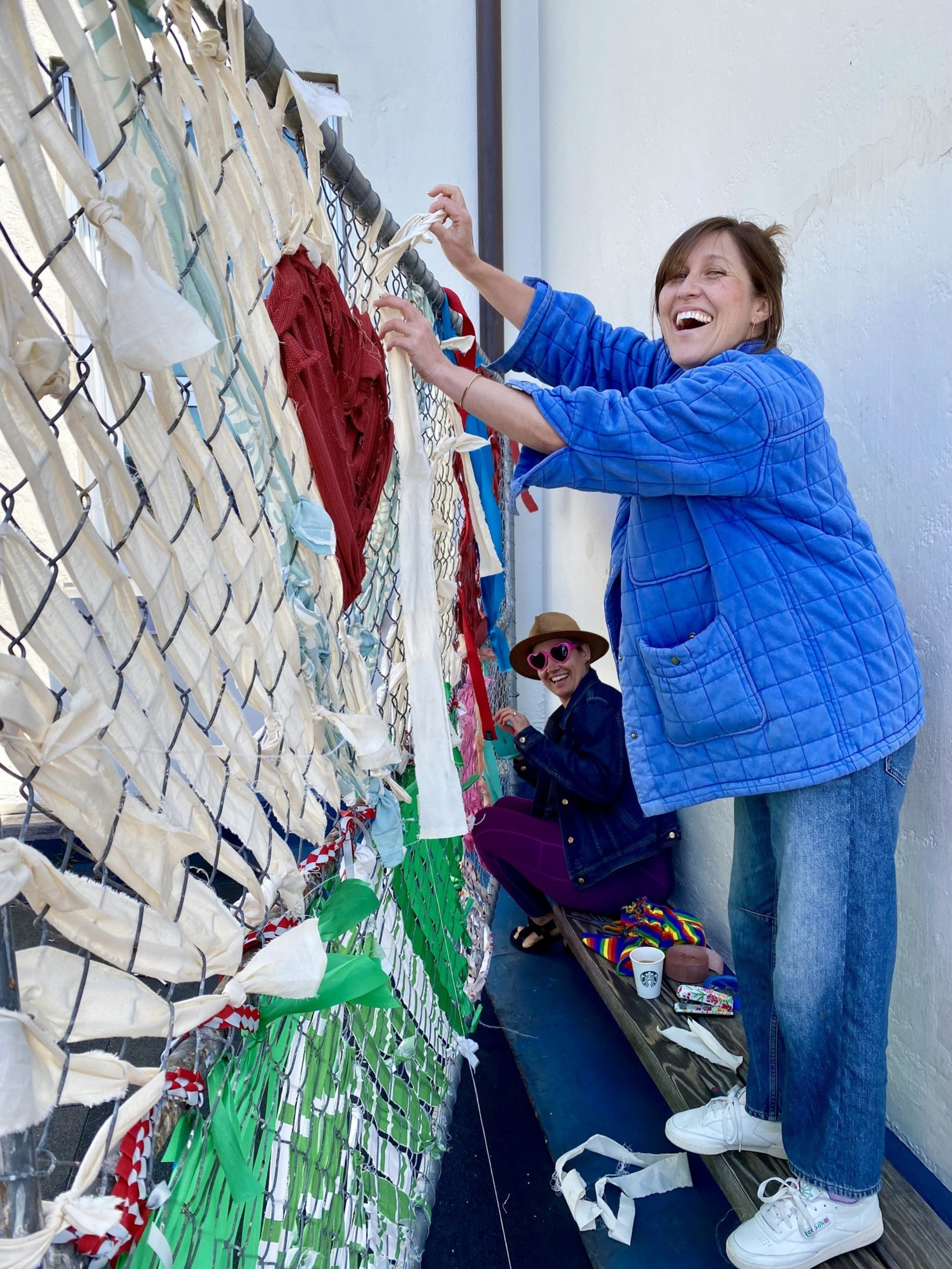 A photo of community members decorating a fence.