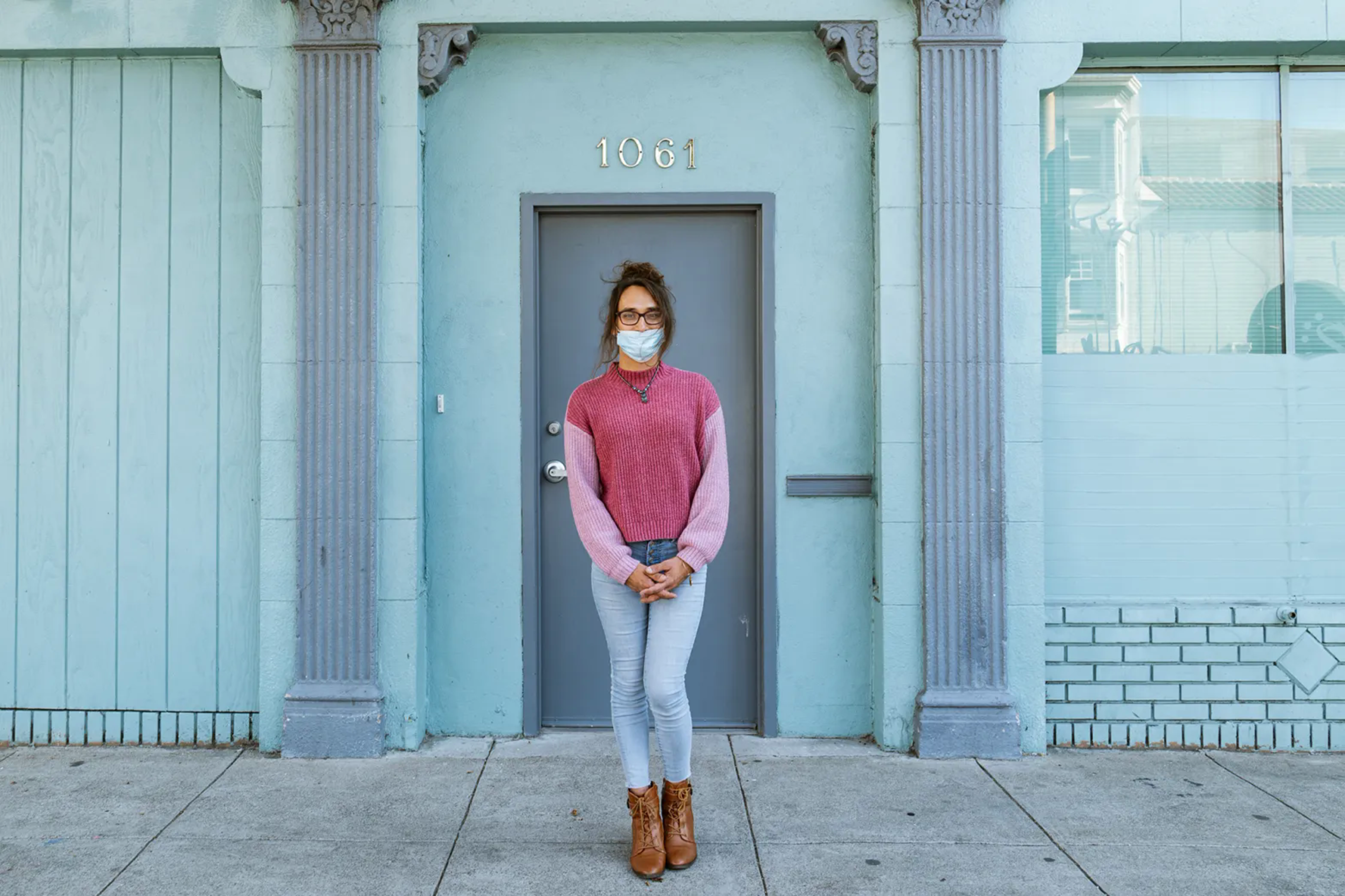 Young person stands in front of a blue door