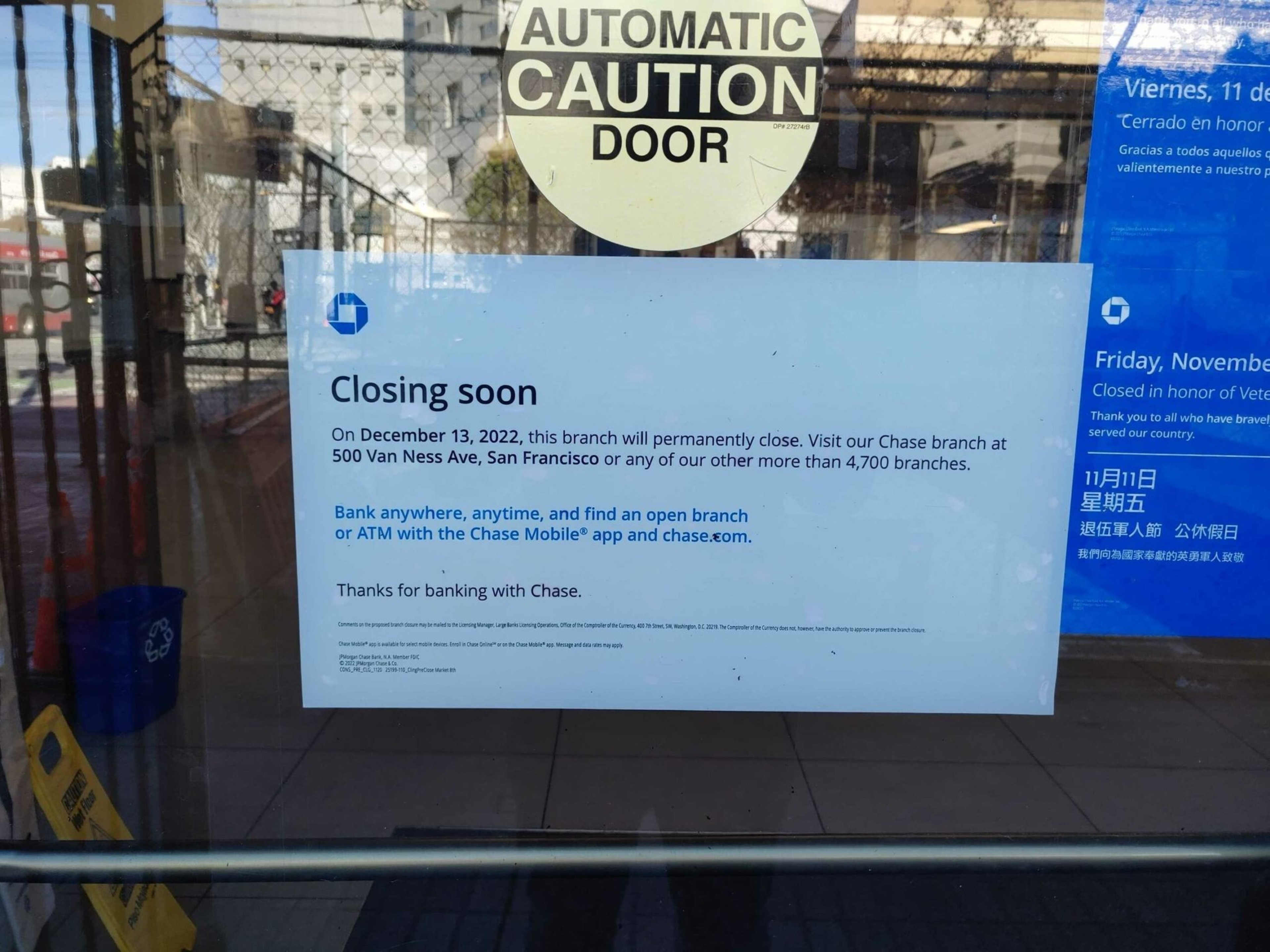 A sign on a glass door announces that the Chase branch will permanently close on December 13, 2022, directing customers to nearby branches and online services.