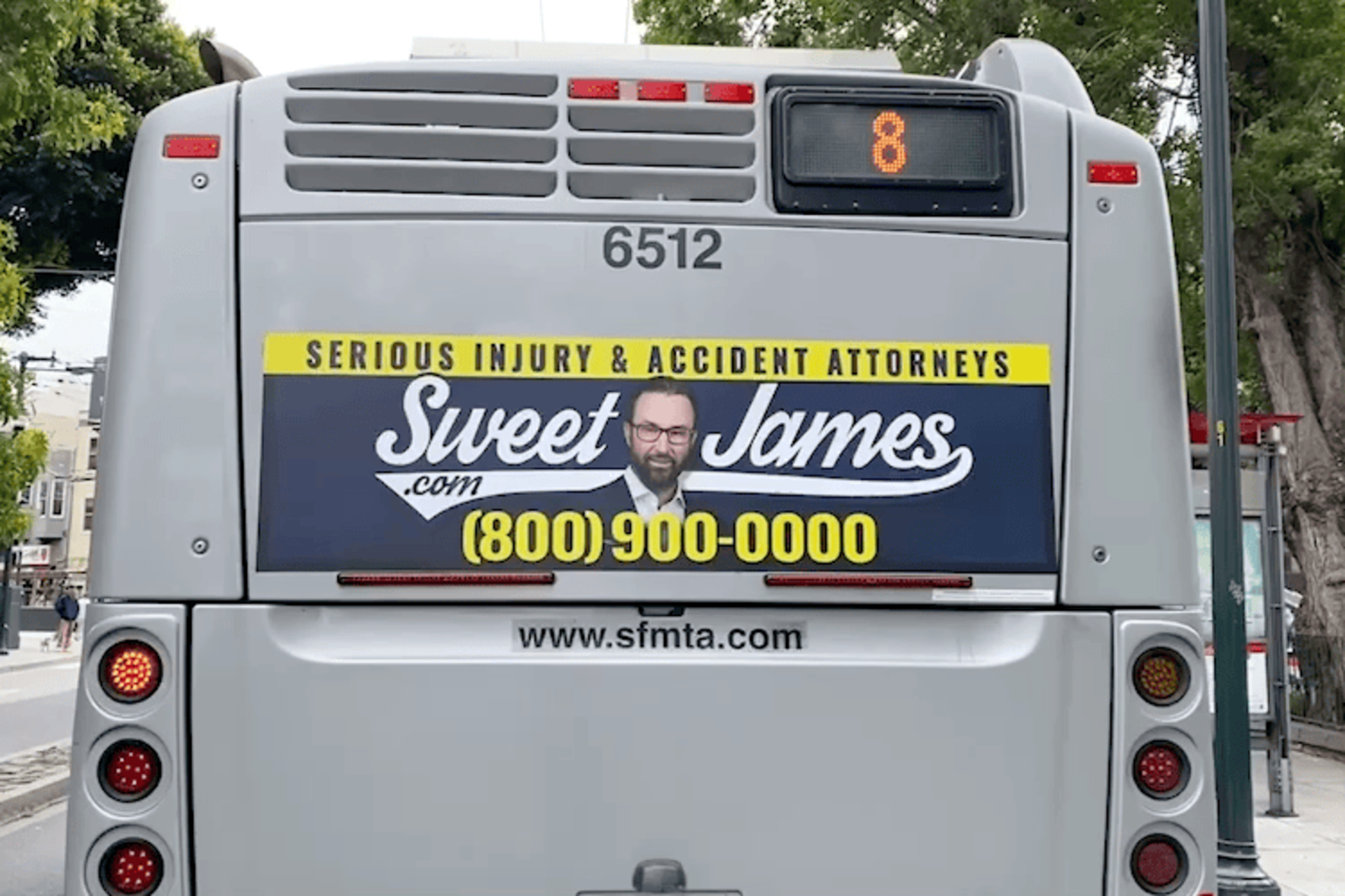 The back of a bus displays an ad for "Sweet James" attorneys specializing in serious injury and accidents, with a photo of a man and the phone number (800) 900-0000.