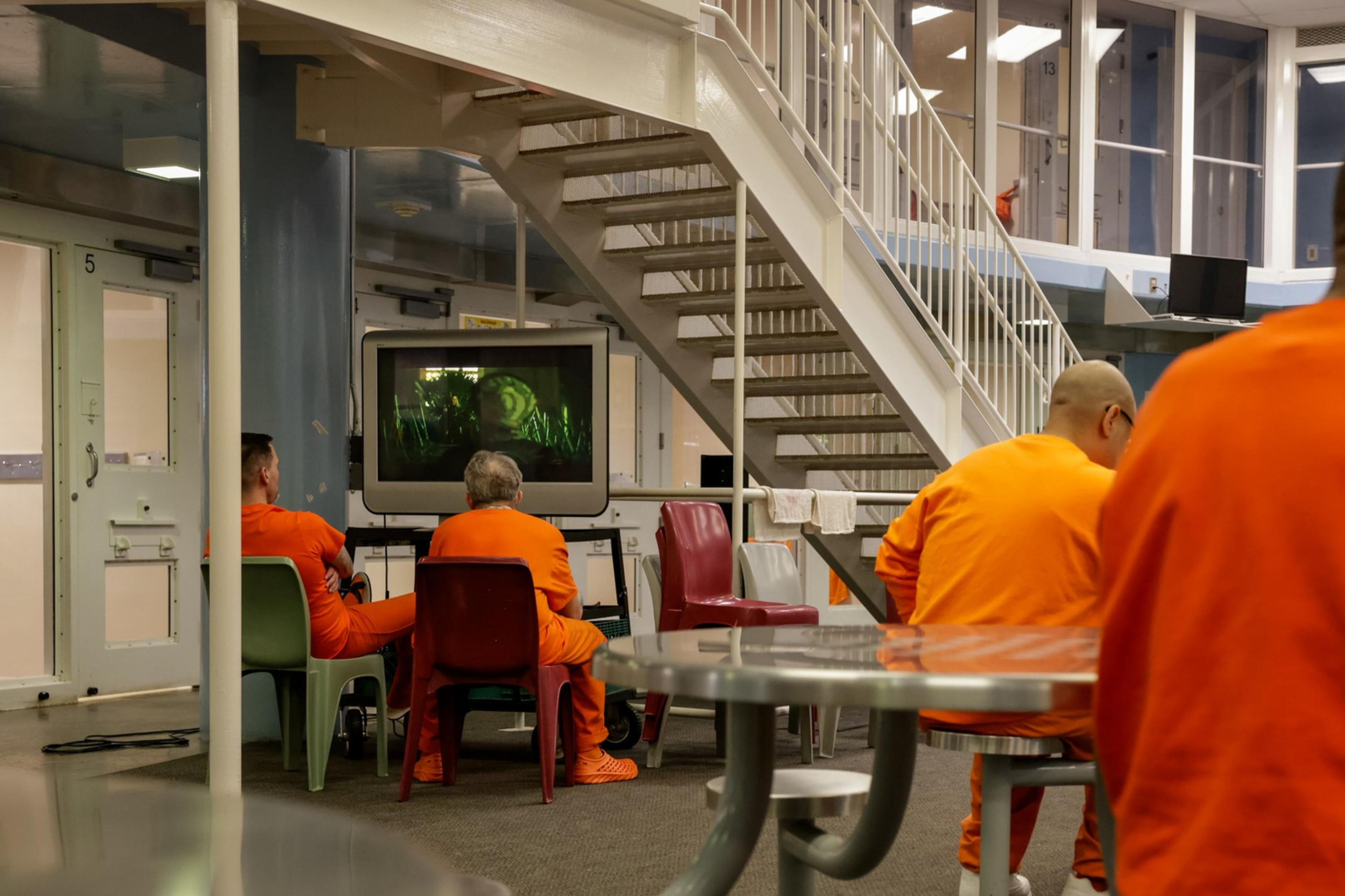Inmates sit at a table in the communal room of the jail cell block.