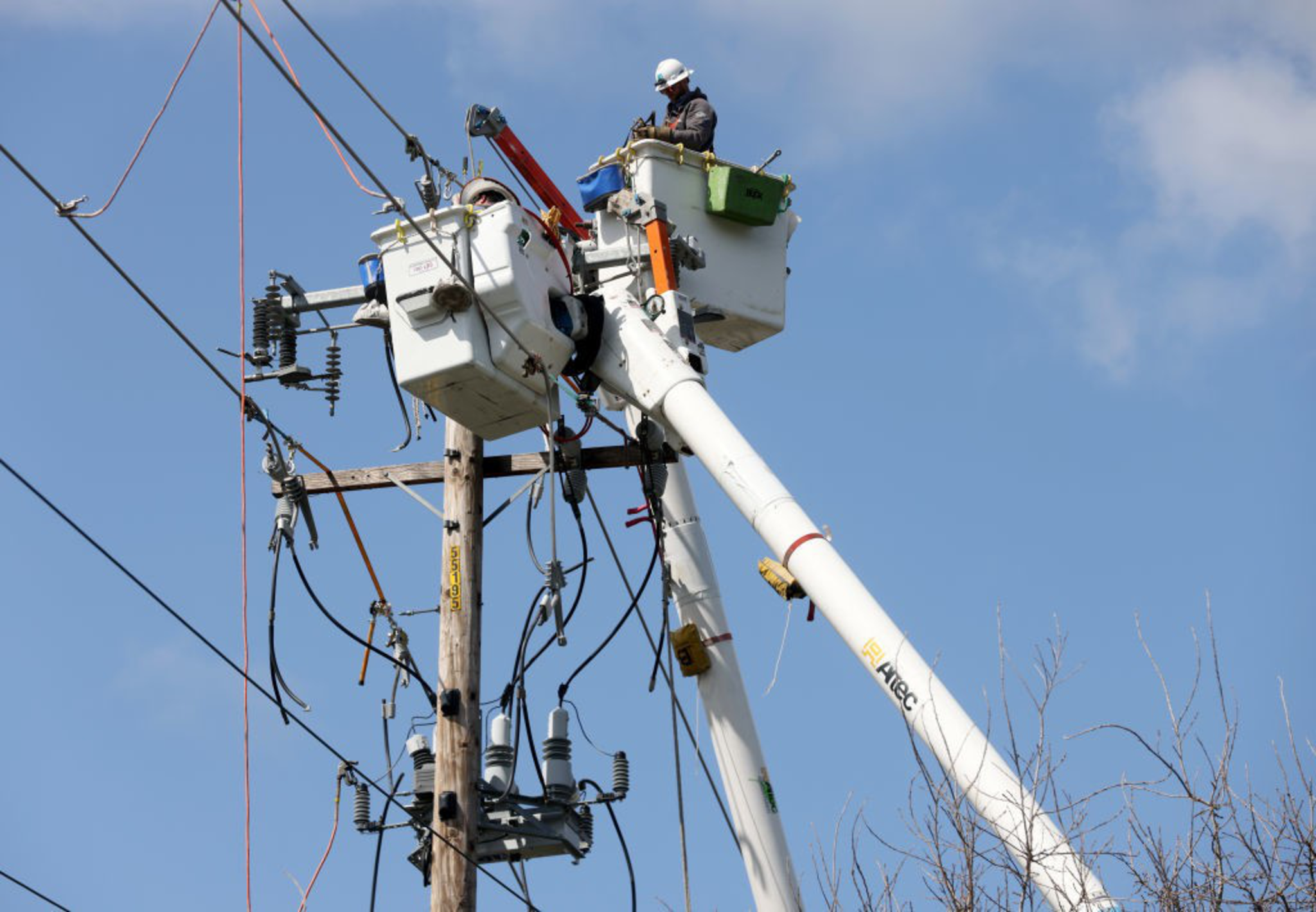 A worker repairs on overhead power line.