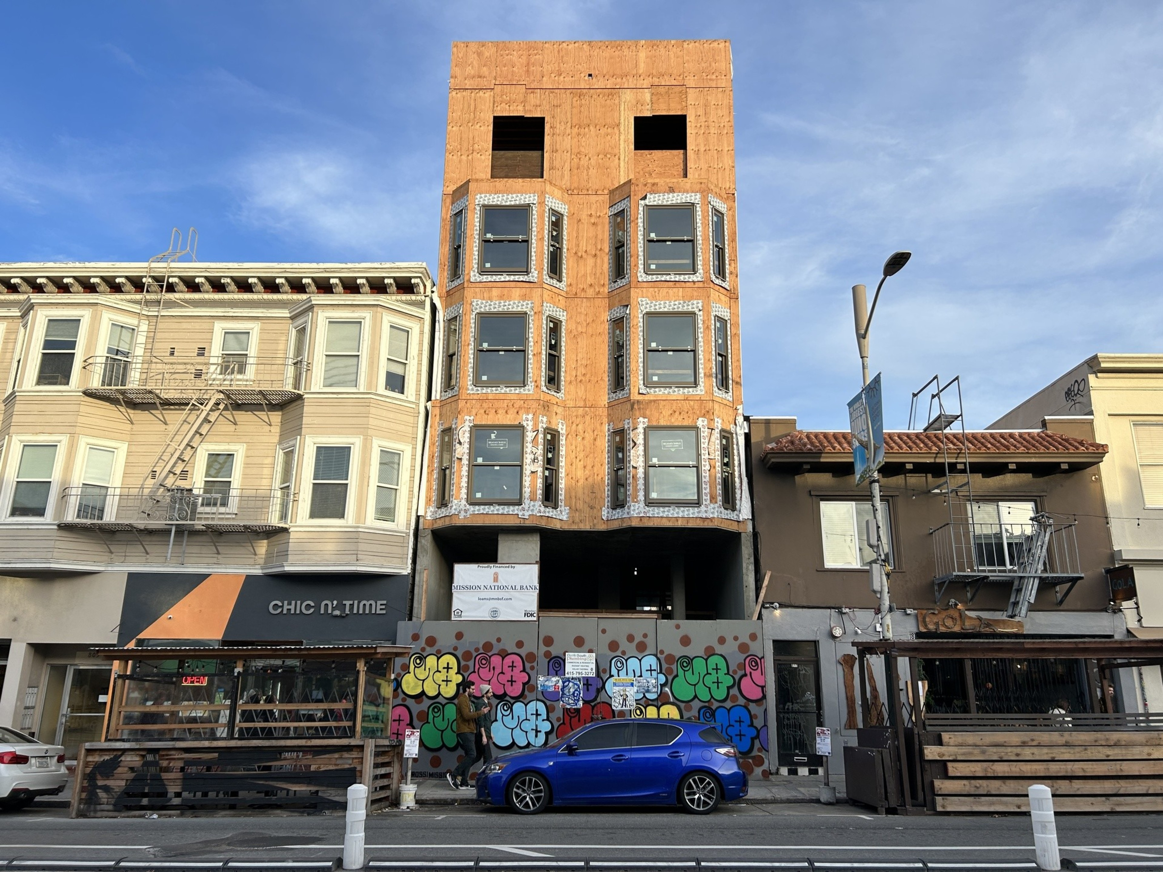 A slender, five-story building is under construction.