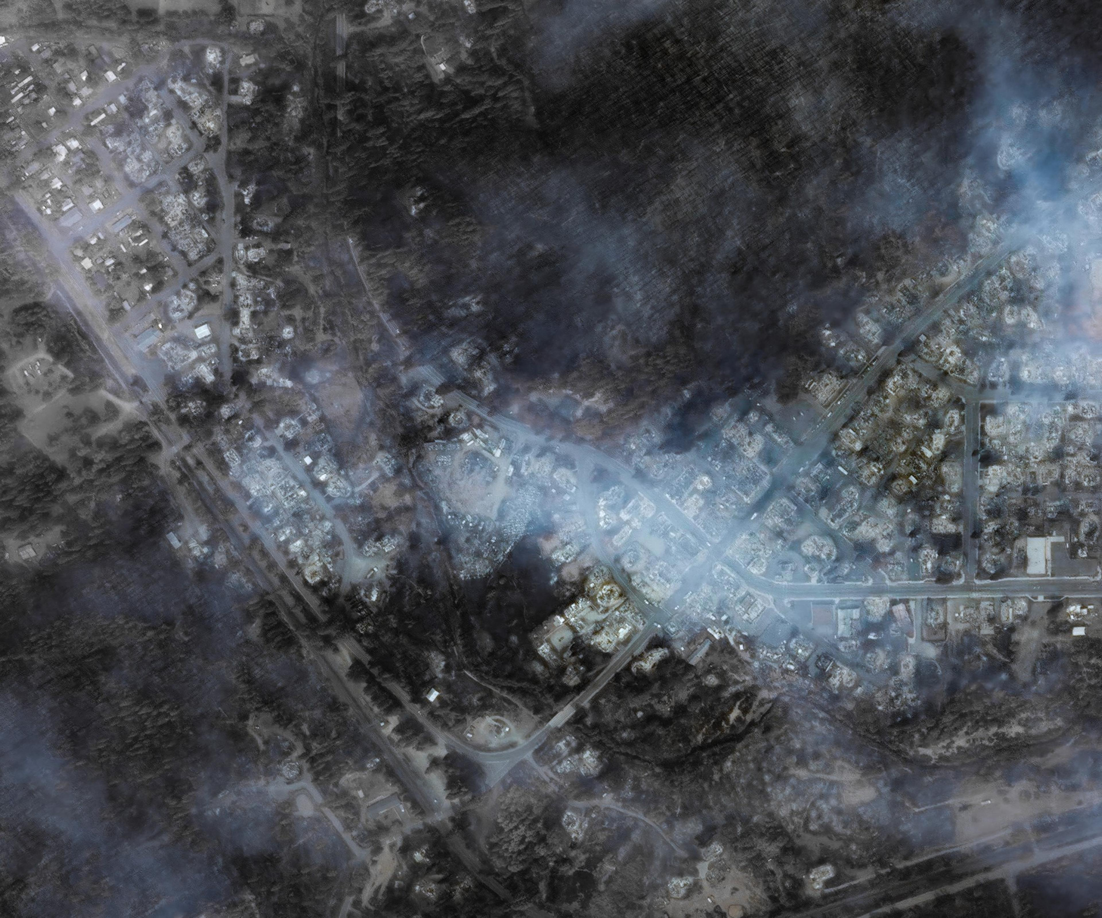 Aerial view of a smoky, obscured landscape with indistinct features suggesting a burned or disaster-stricken area.
