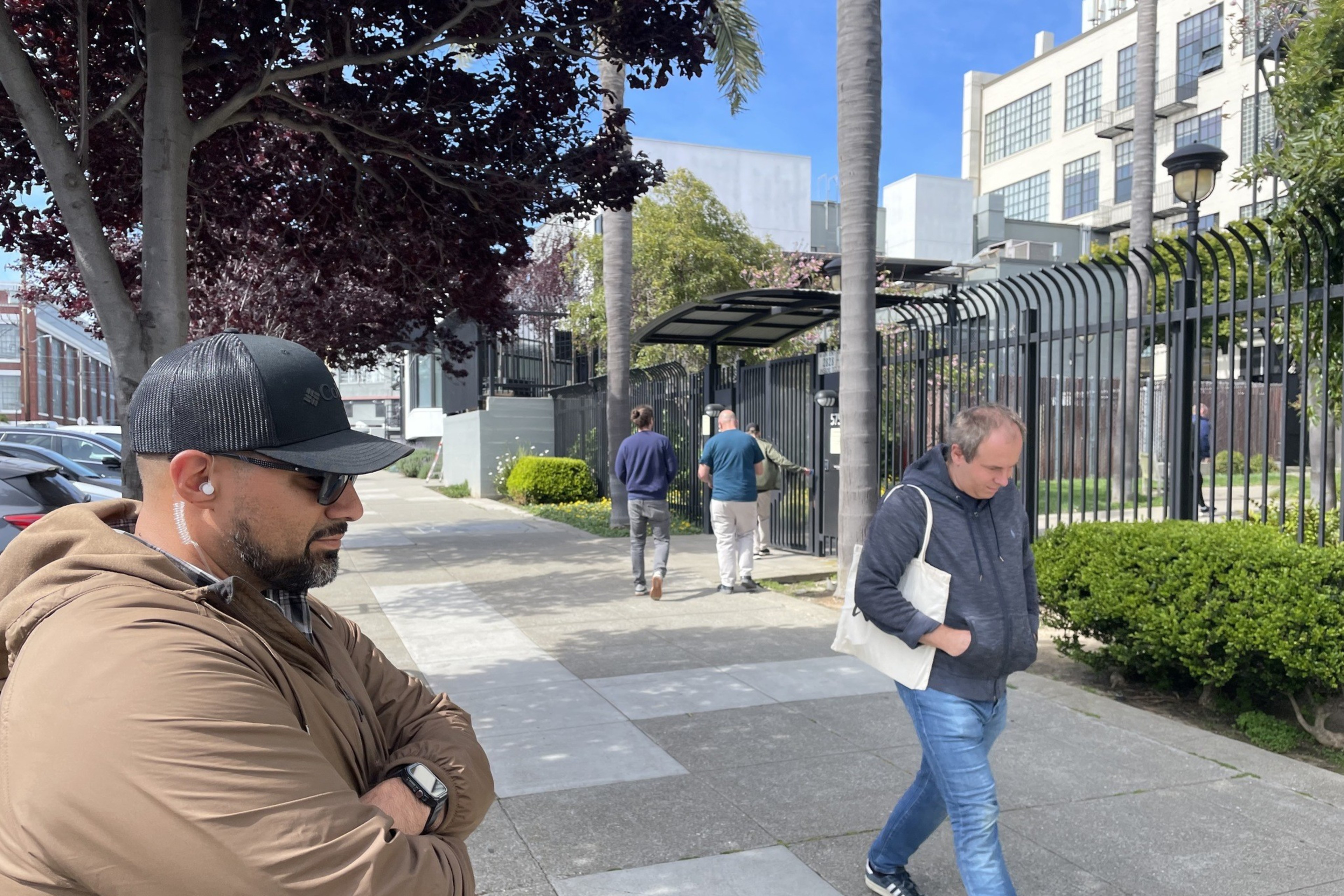 A man watches another man walk past along a sidewalk in a photo.