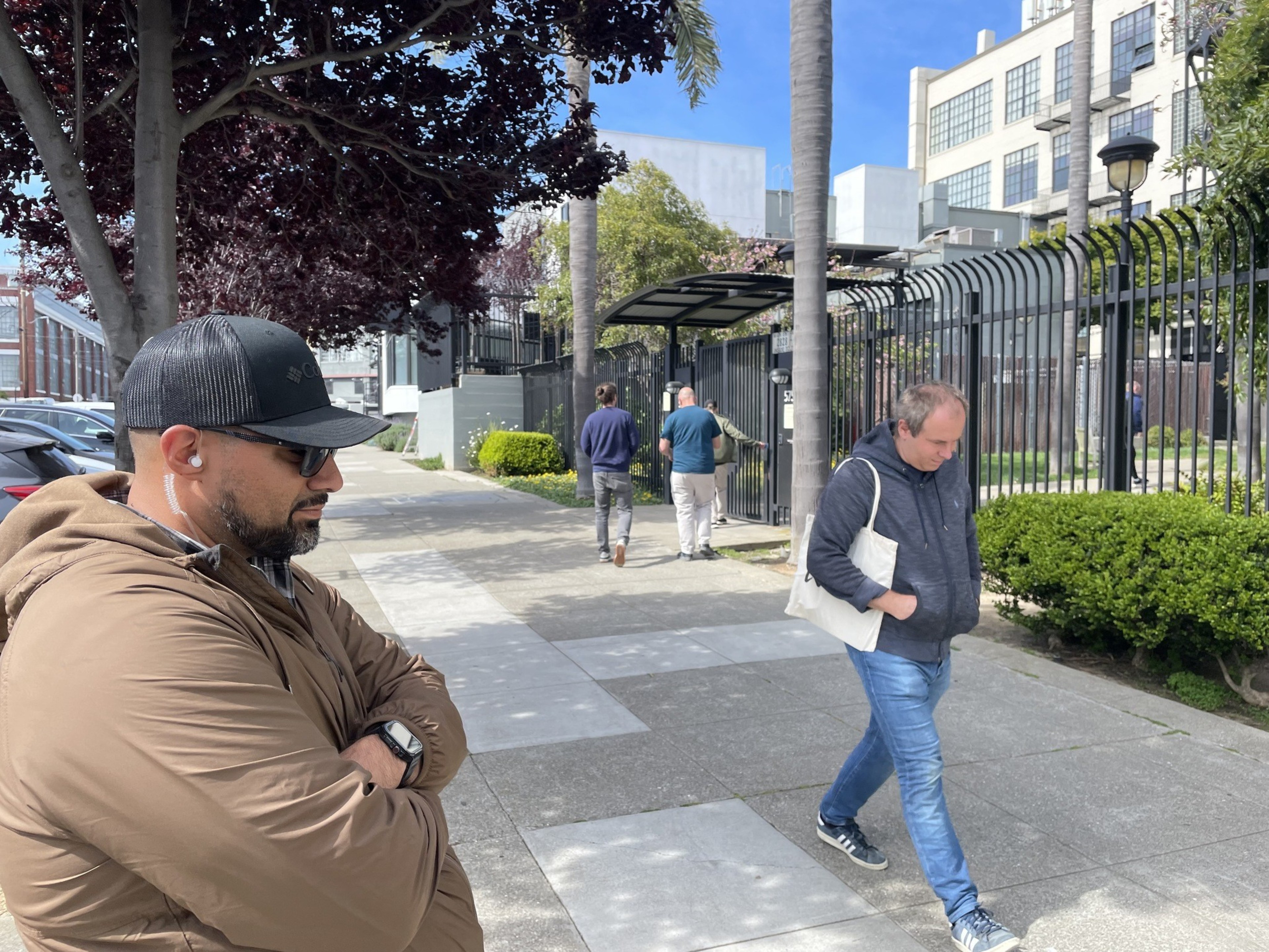 A man watches another man walk past along a sidewalk in a photo.
