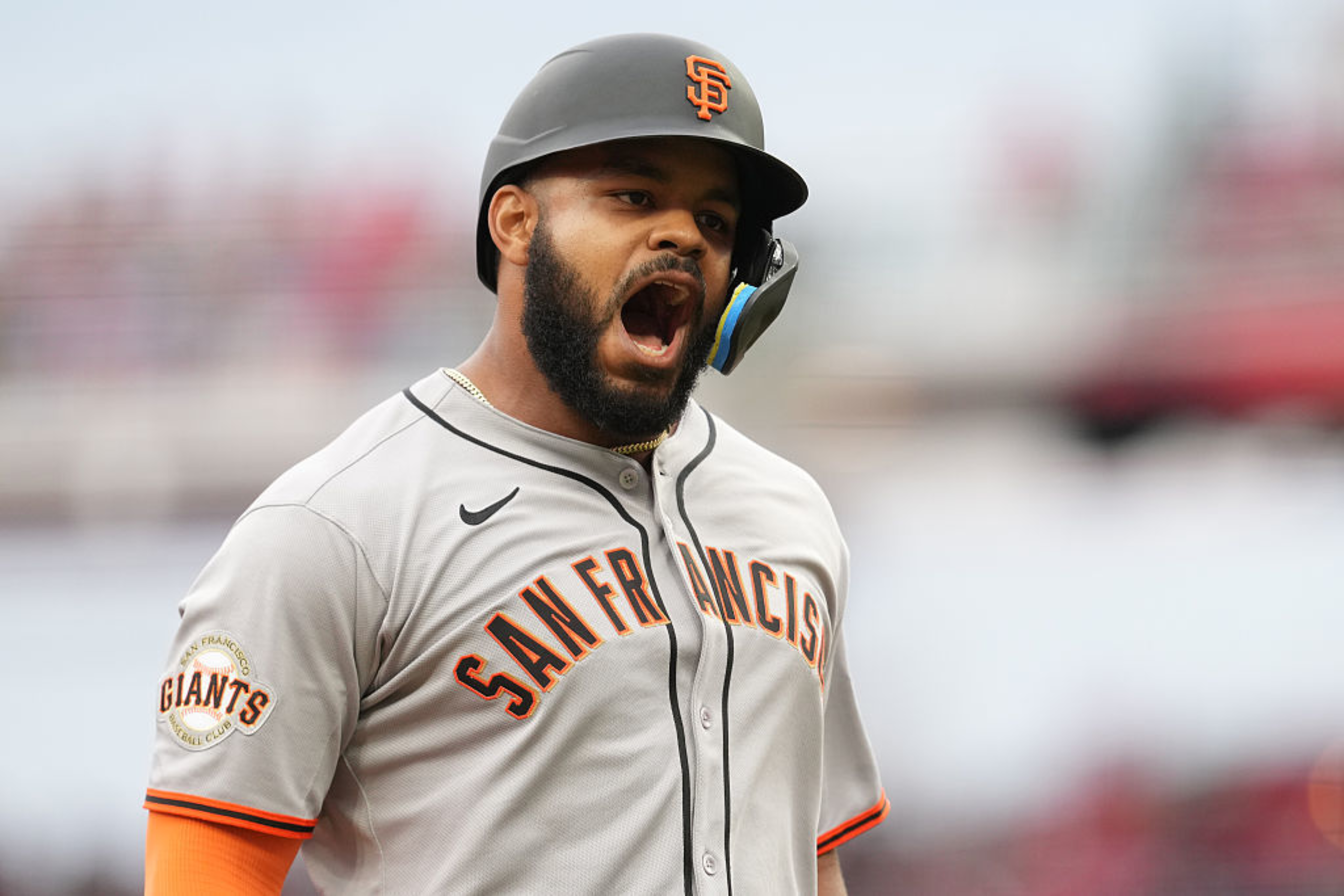 A baseball player in a San Francisco Giants uniform and black helmet is shouting passionately, showing intensity and focus.