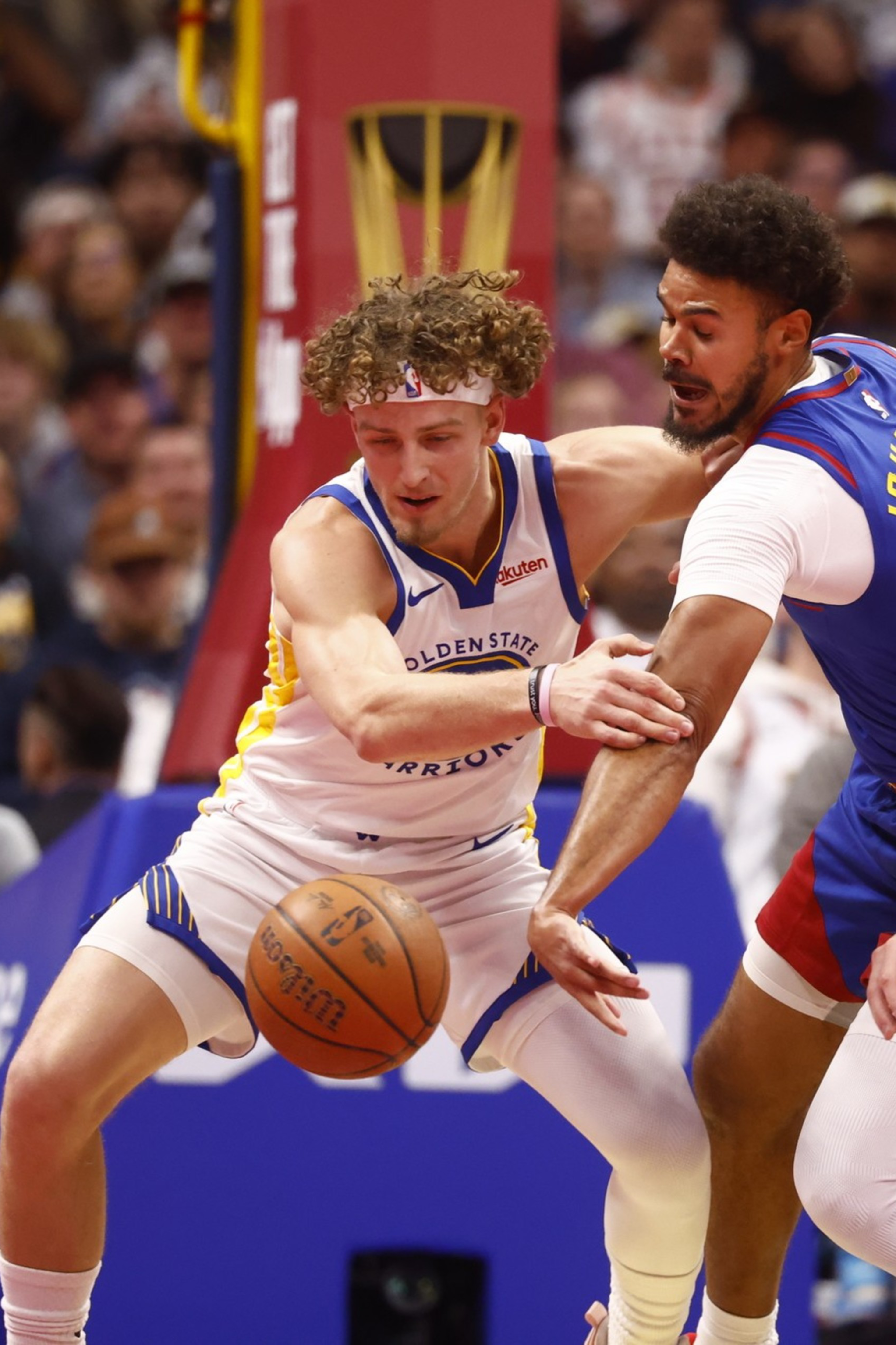 A Golden State Warriors player battles two Denver Nuggets defenders for control of a loose basketball during a game.