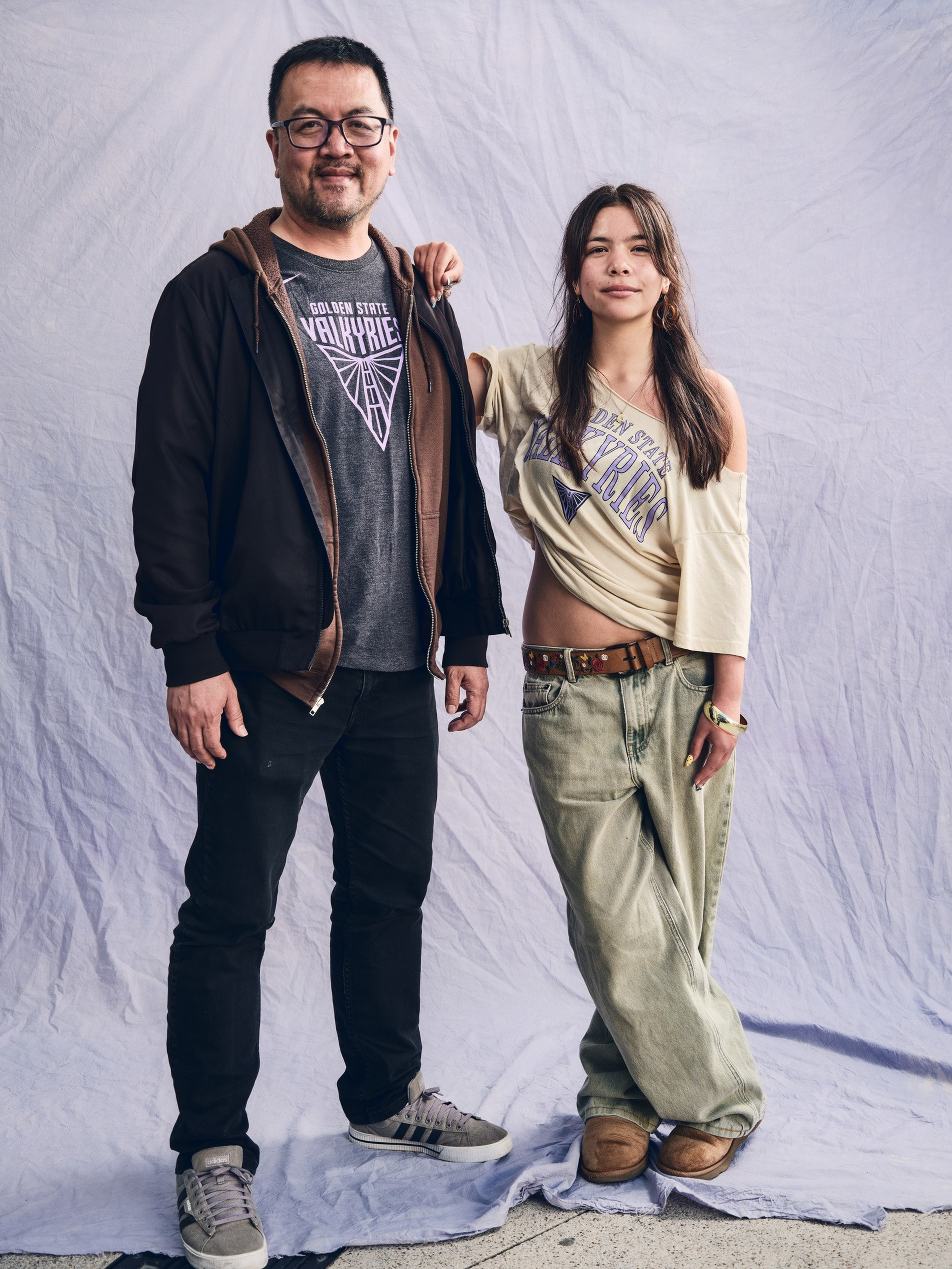 A man and woman stand side by side wearing casual clothes, both with graphic t-shirts that read “Golden State Valkyrie.”