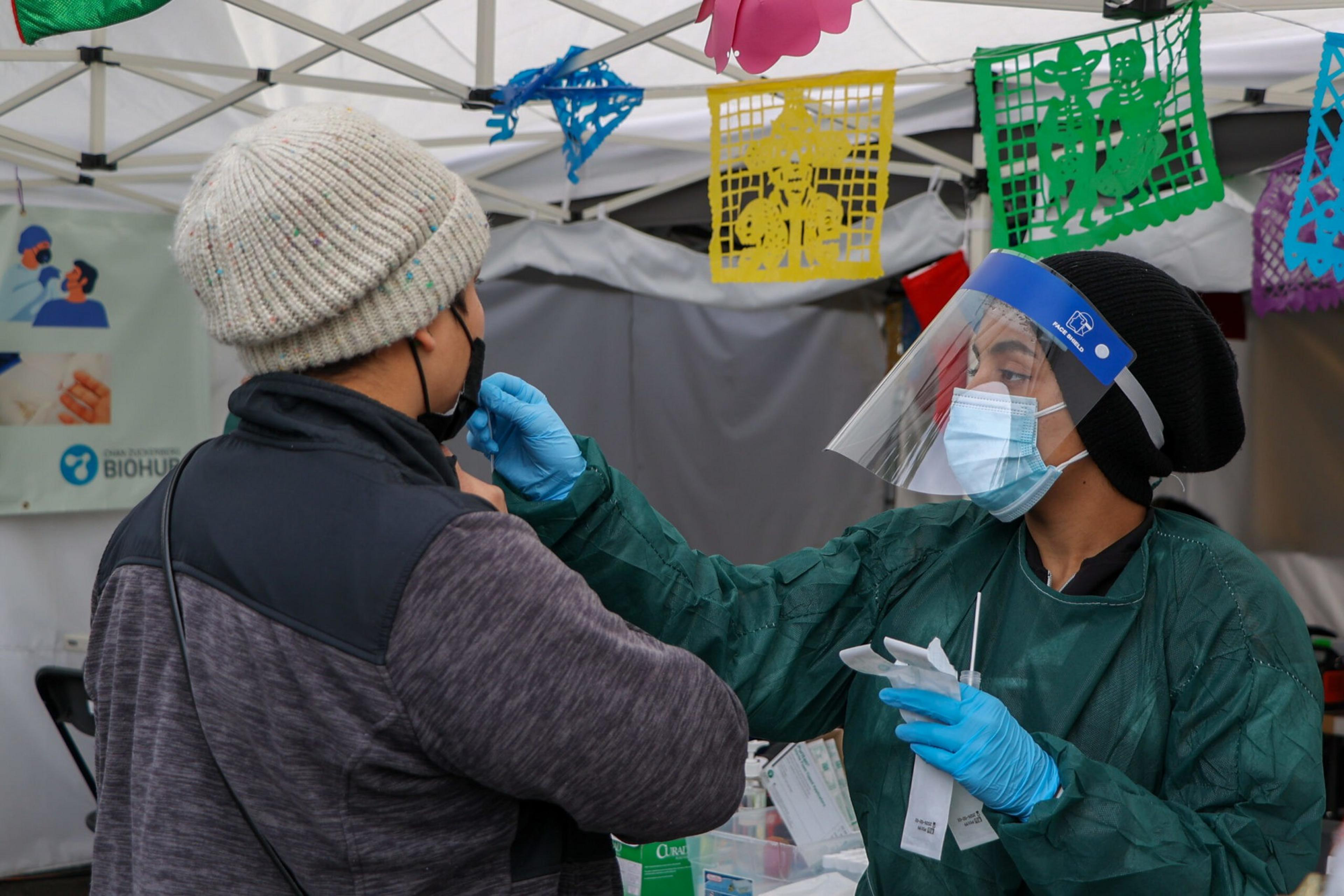 a woman in a mask swabs a mans nose