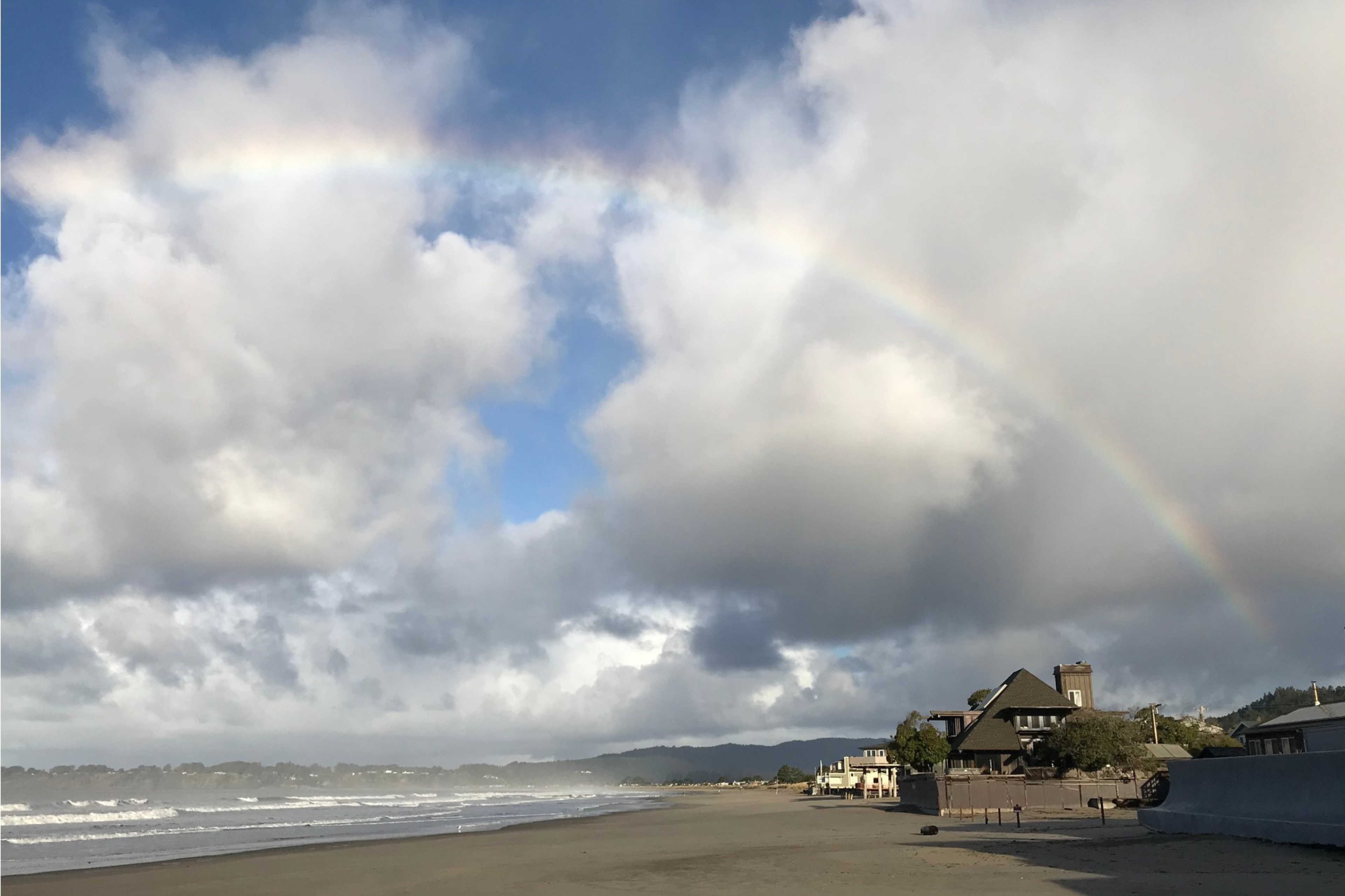 A cloudy day at the beach with a hint of a rainbow.