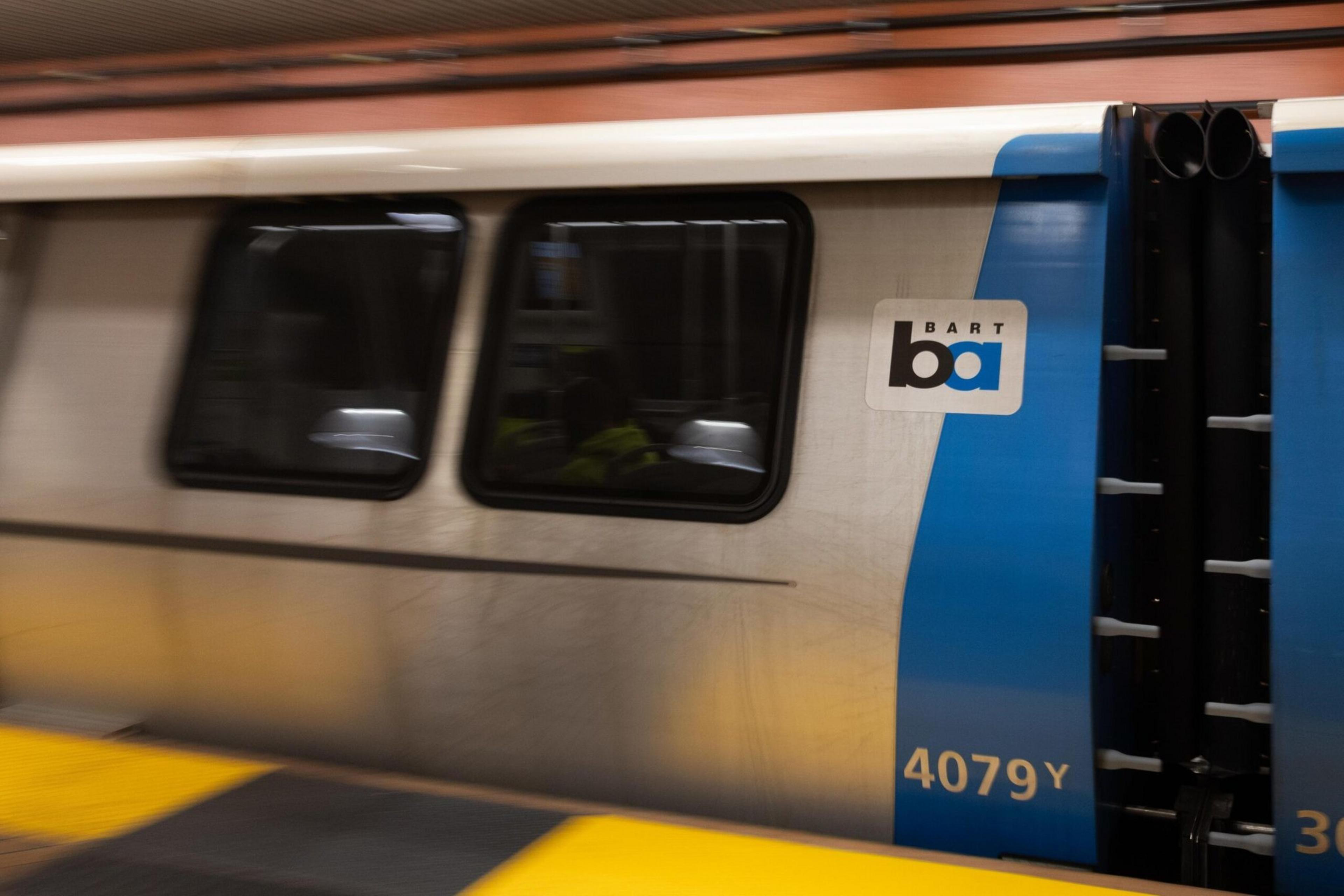 A BART train speeds past a passenger platform