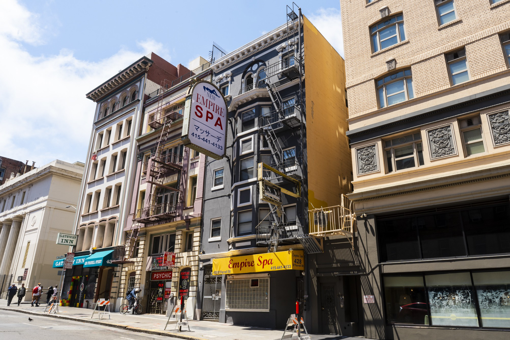 A street view shows a row of urban buildings with diverse facades. A prominent sign for "Empire Spa" hangs in front, and people walk along the sidewalk.