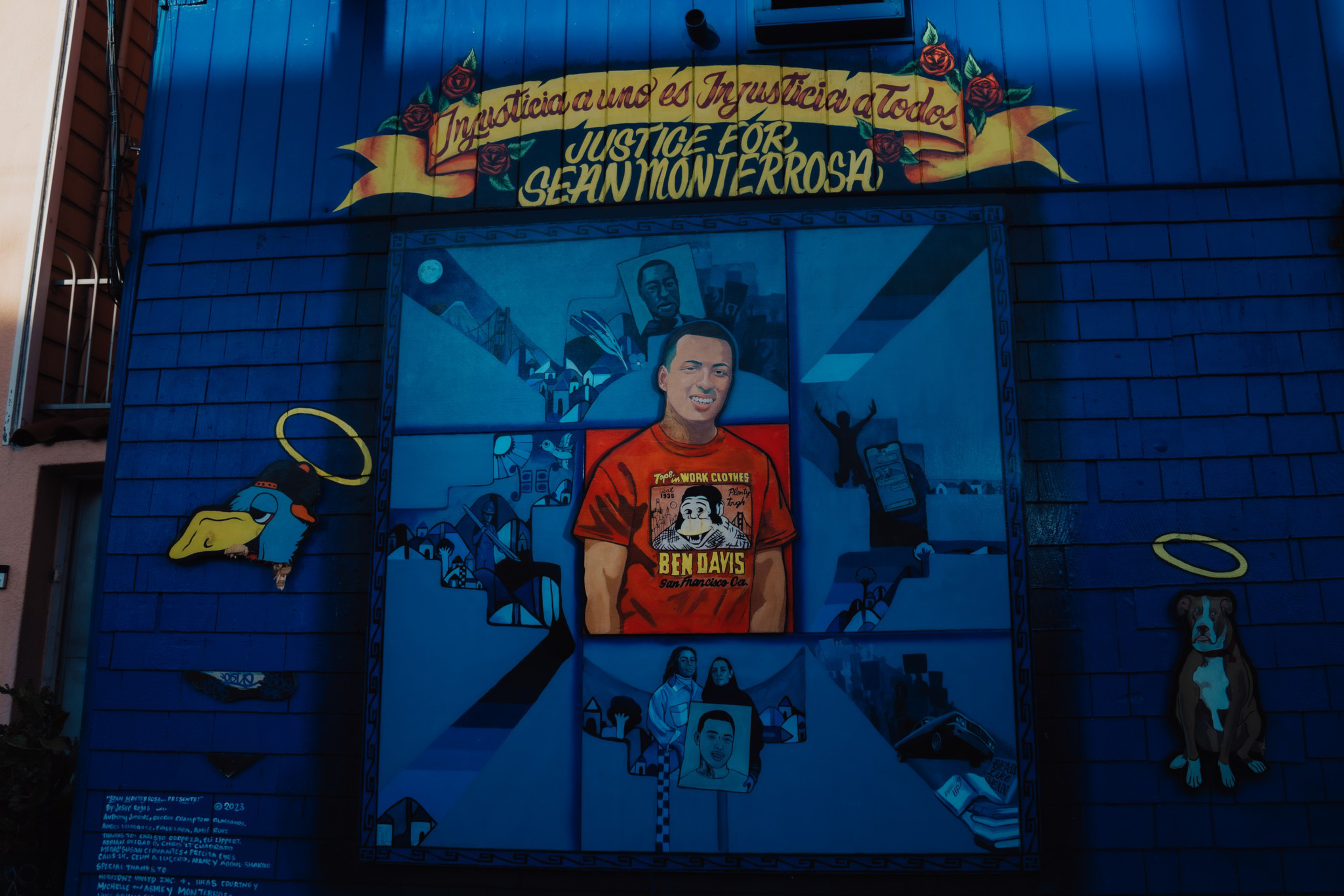 A mural with a central portrait of a man in a red shirt, surrounded by smaller images, two haloed animals, and the text “Justice for Sean Monterrosa.”