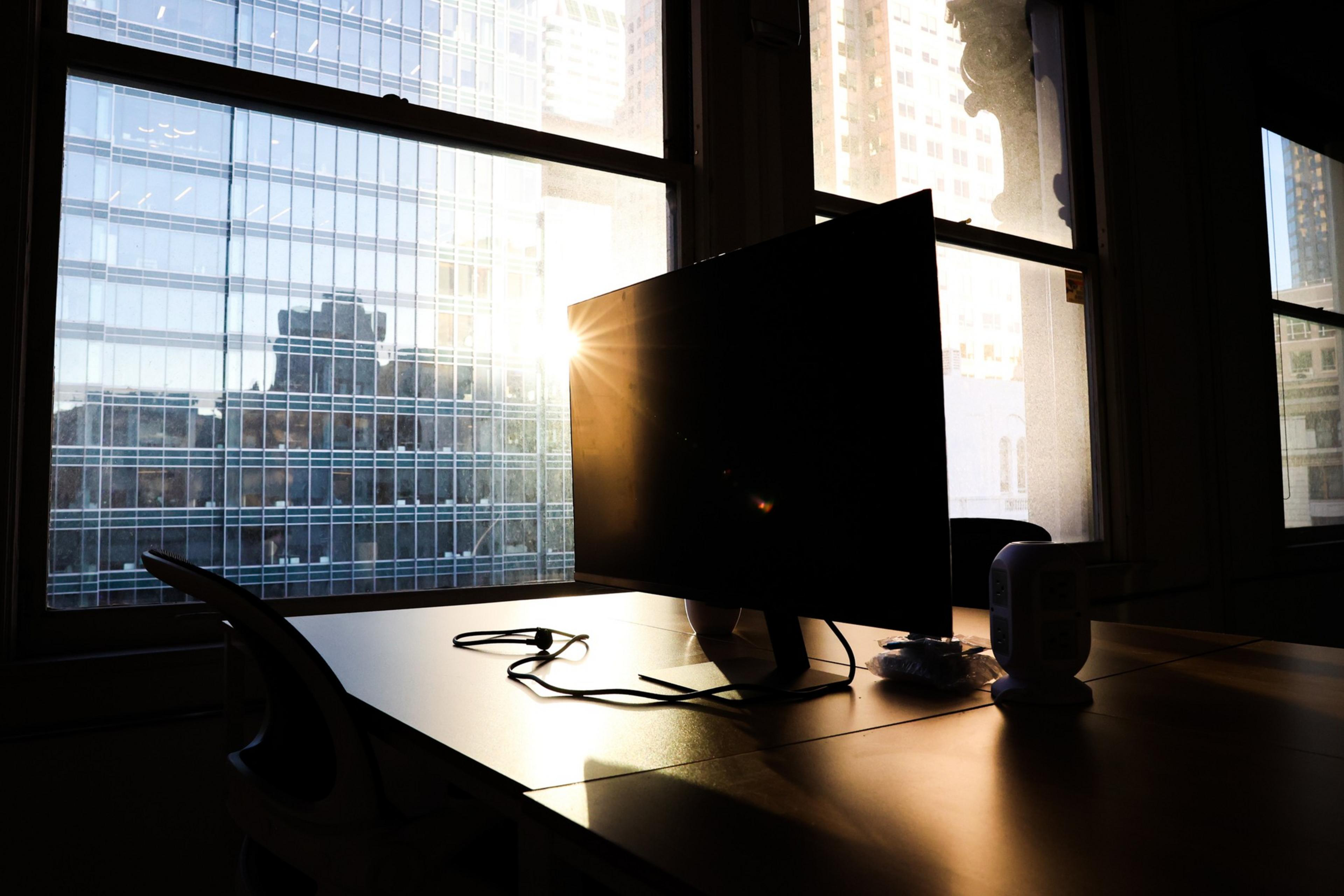 An empty desk by the window with the sun peeking