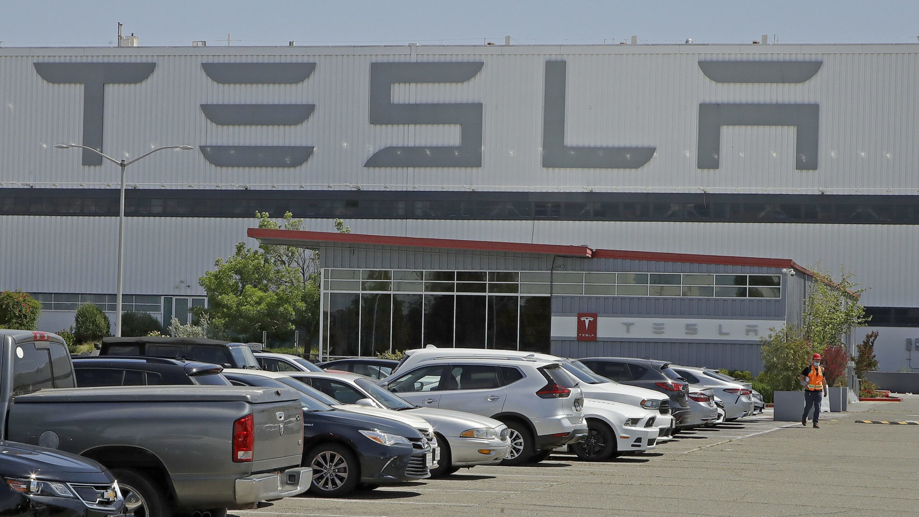 A man walks in the Tesla plant parking lot in Fremont in May 2020.