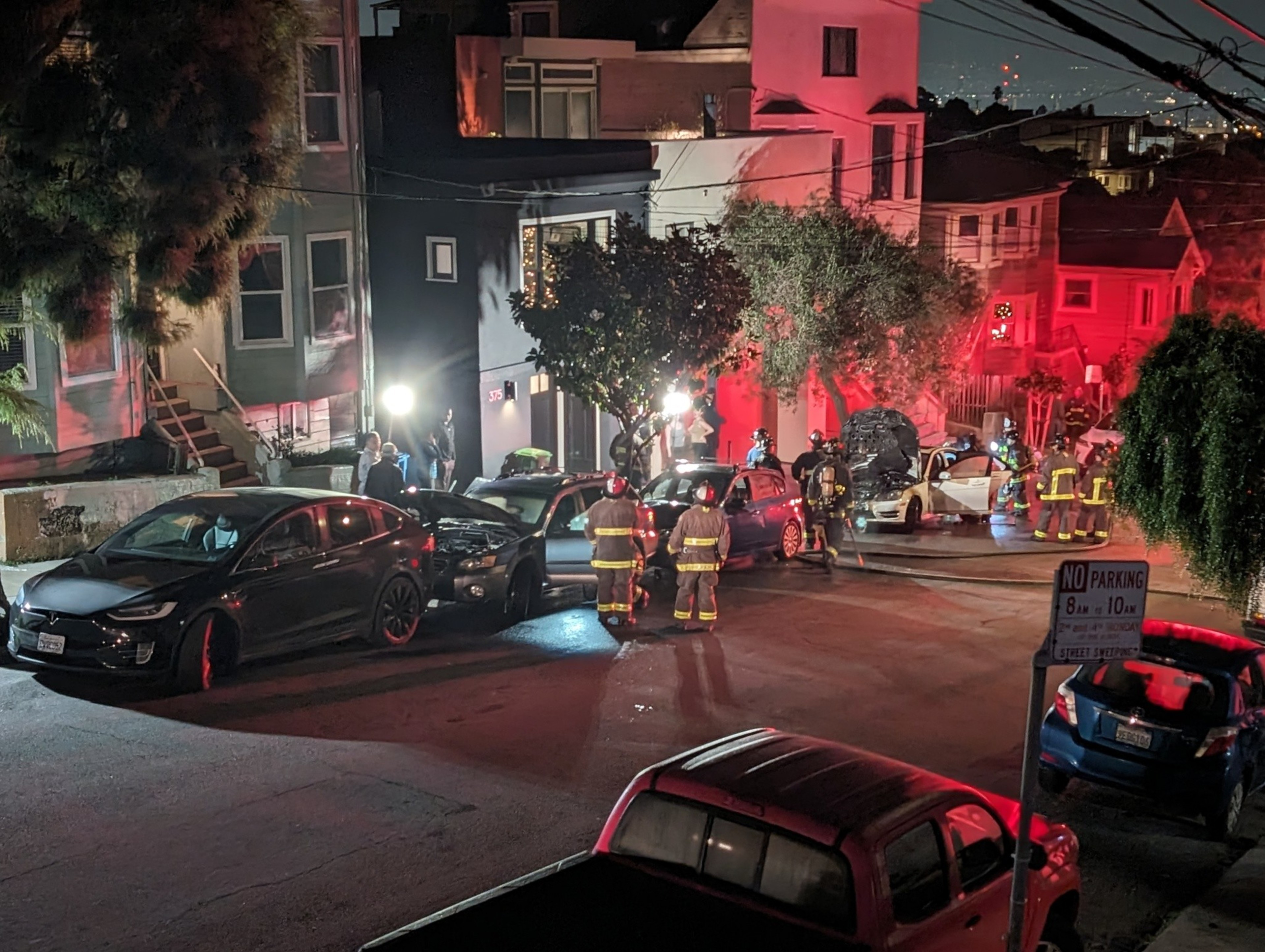 Fire trucks and firefighters appear in a darkened street.