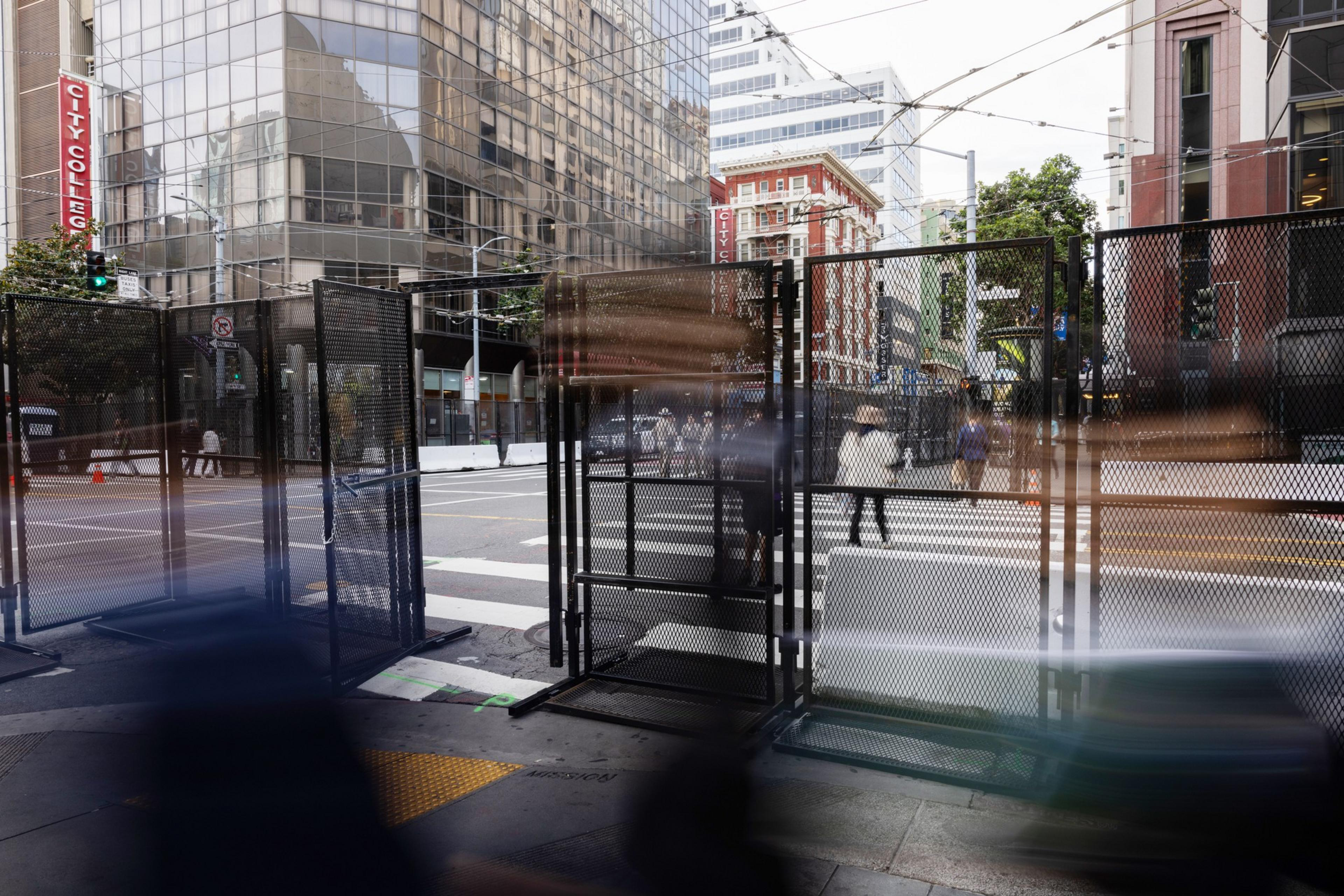 A large black fence on a city street corner.