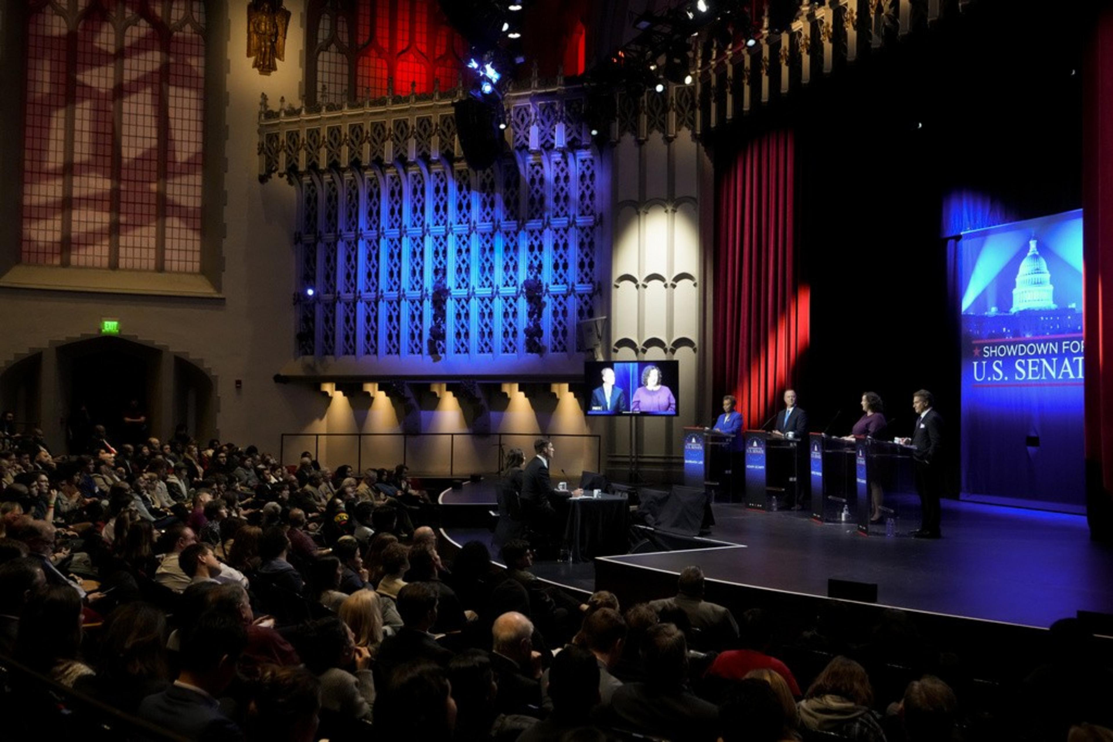 Four people on stage in front of a sign saying &quot;Showdown for U.S. Senate.&quot;