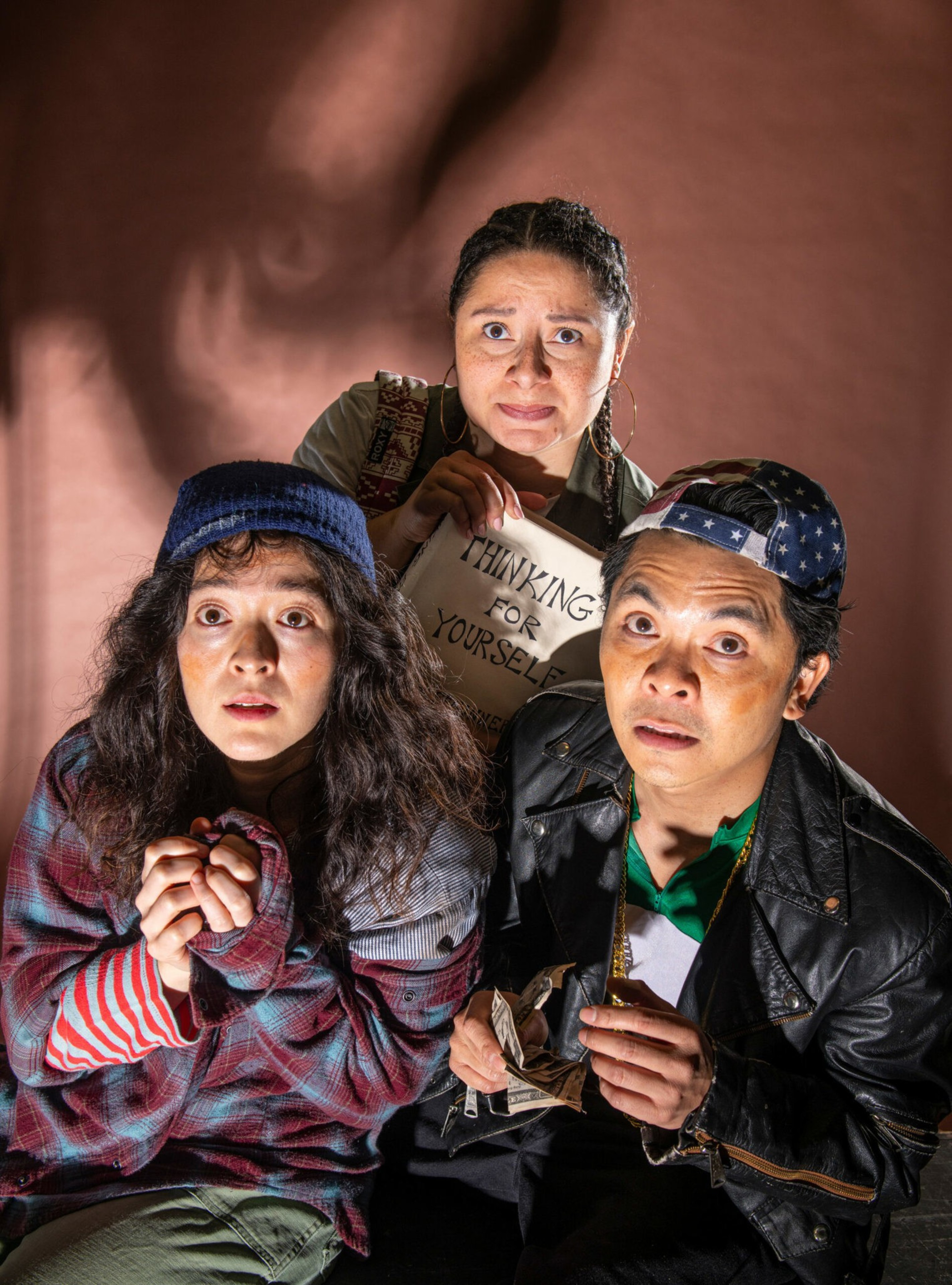 Three people look up with worried expressions; one holds a sign reading "THINKING FOR YOURSELF," another clutches crumpled money, and a third wears a blue knit hat.