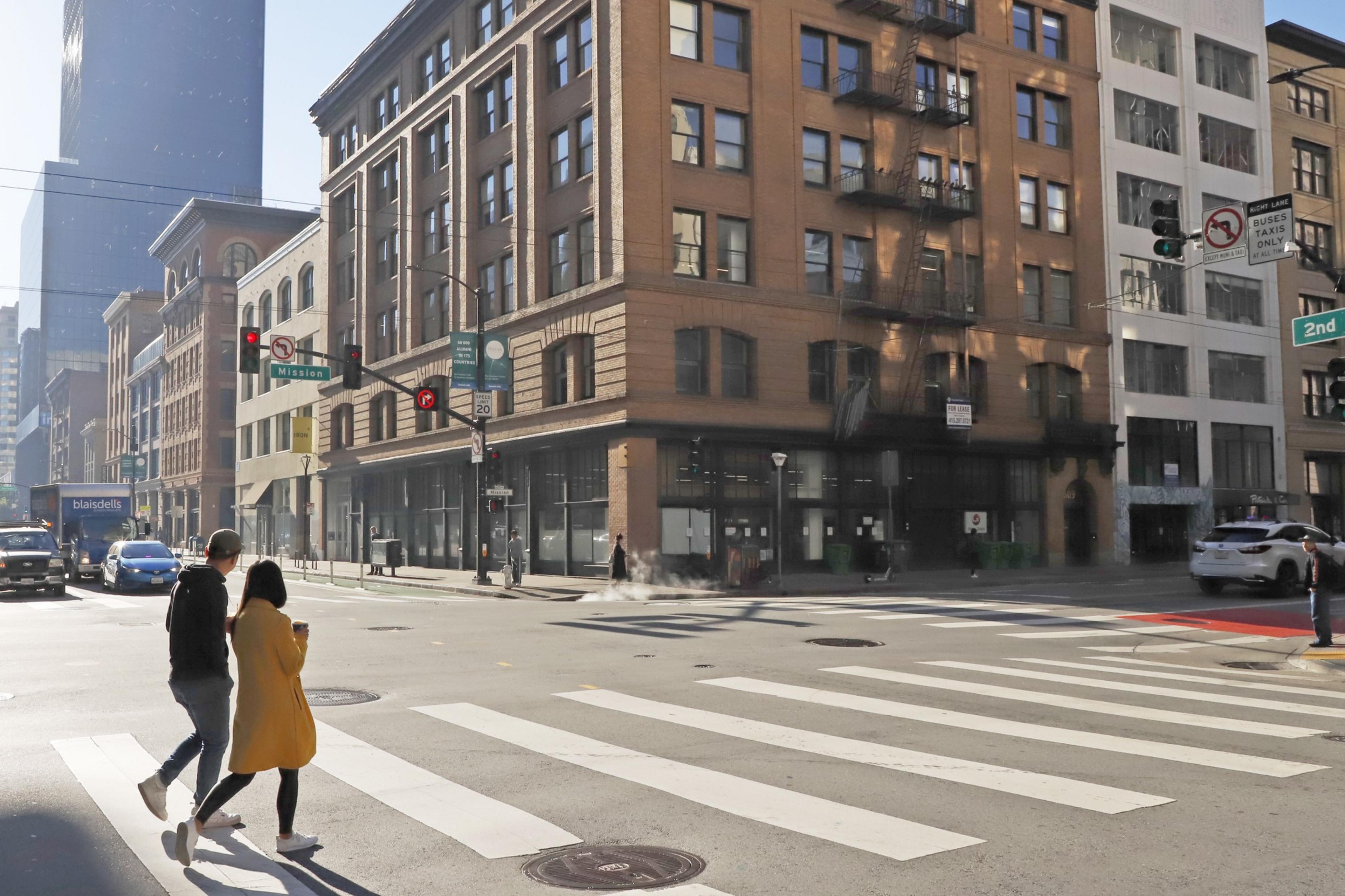 Two pedesrtians walk through an empty intersection of Mission and 2nd St. in San Francisco