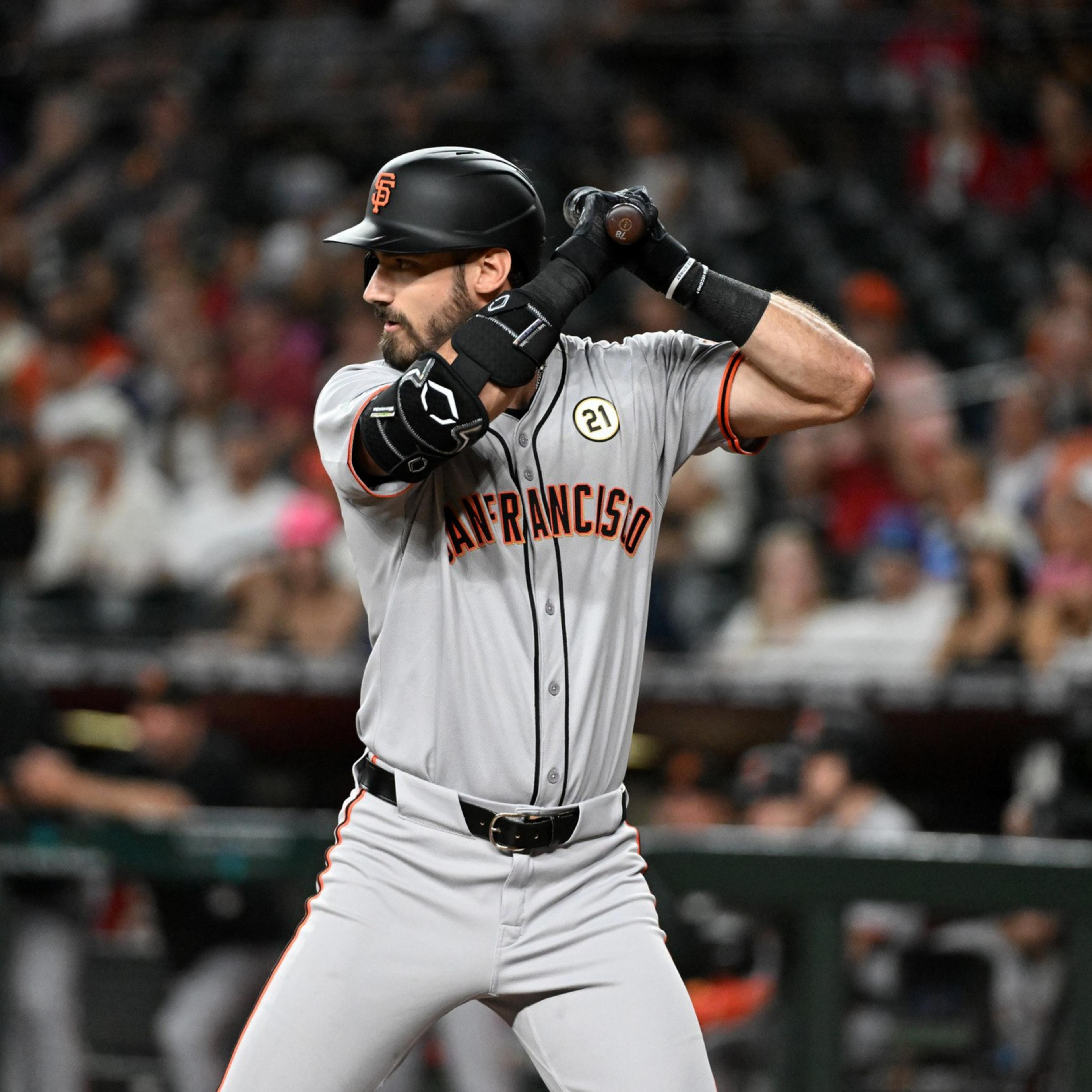 A San Francisco Giants baseball player prepares to bat, gripping the bat with both hands in a ready stance, wearing a gray uniform and black helmet.