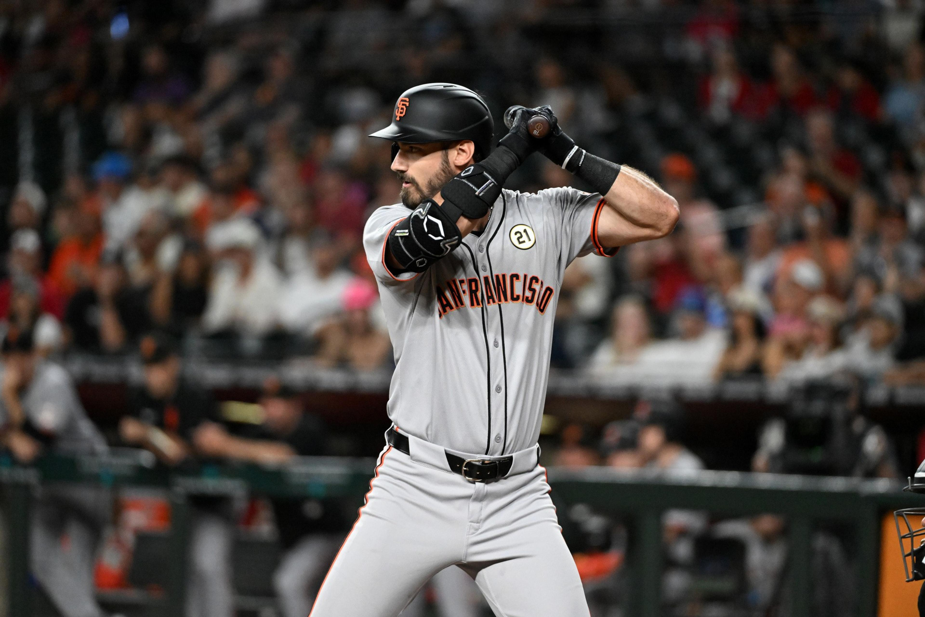A San Francisco Giants baseball player prepares to bat, gripping the bat with both hands in a ready stance, wearing a gray uniform and black helmet.