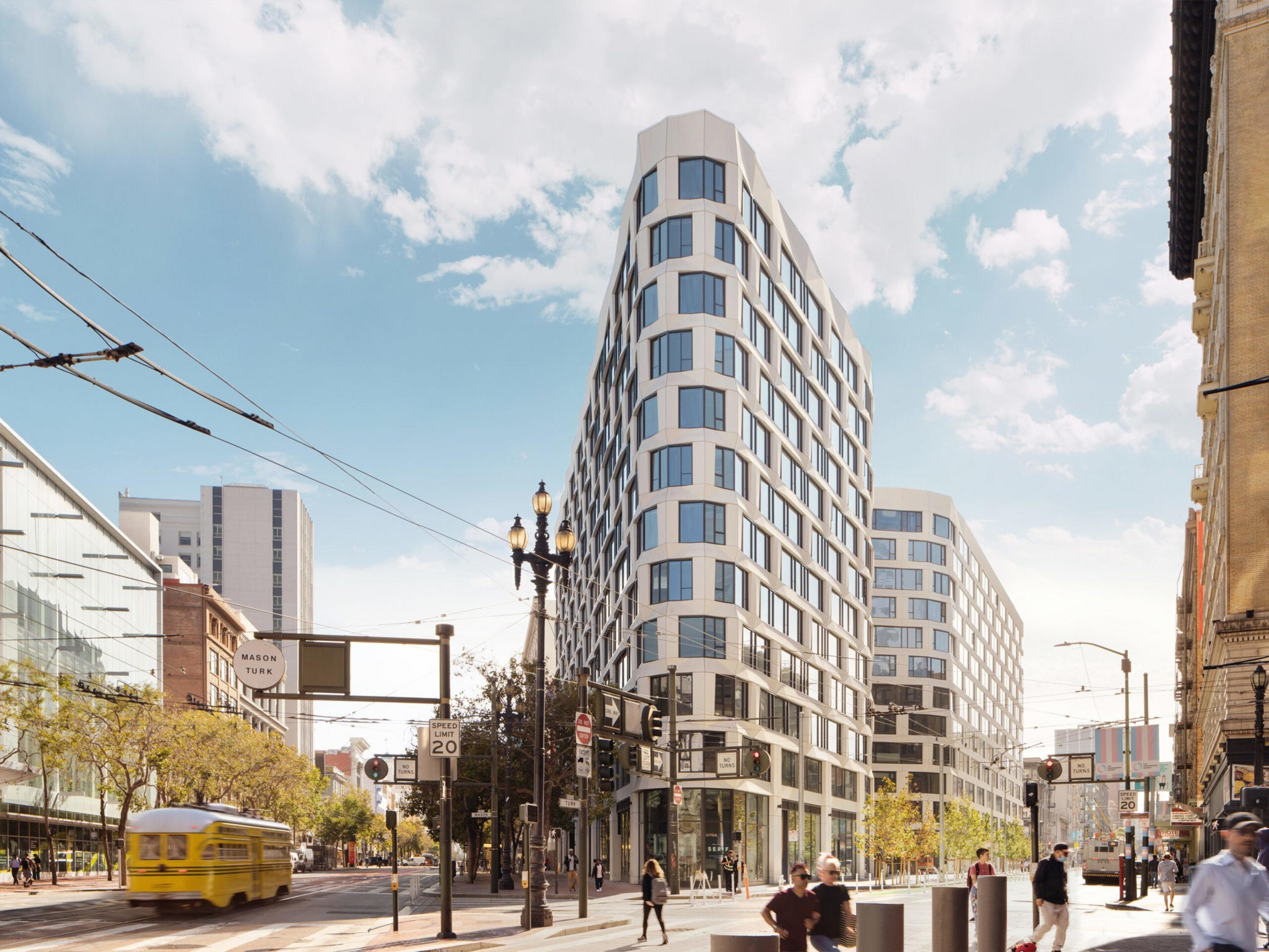 A modern, white, curved-corner building with large windows stands at a busy city intersection under a partly cloudy sky.