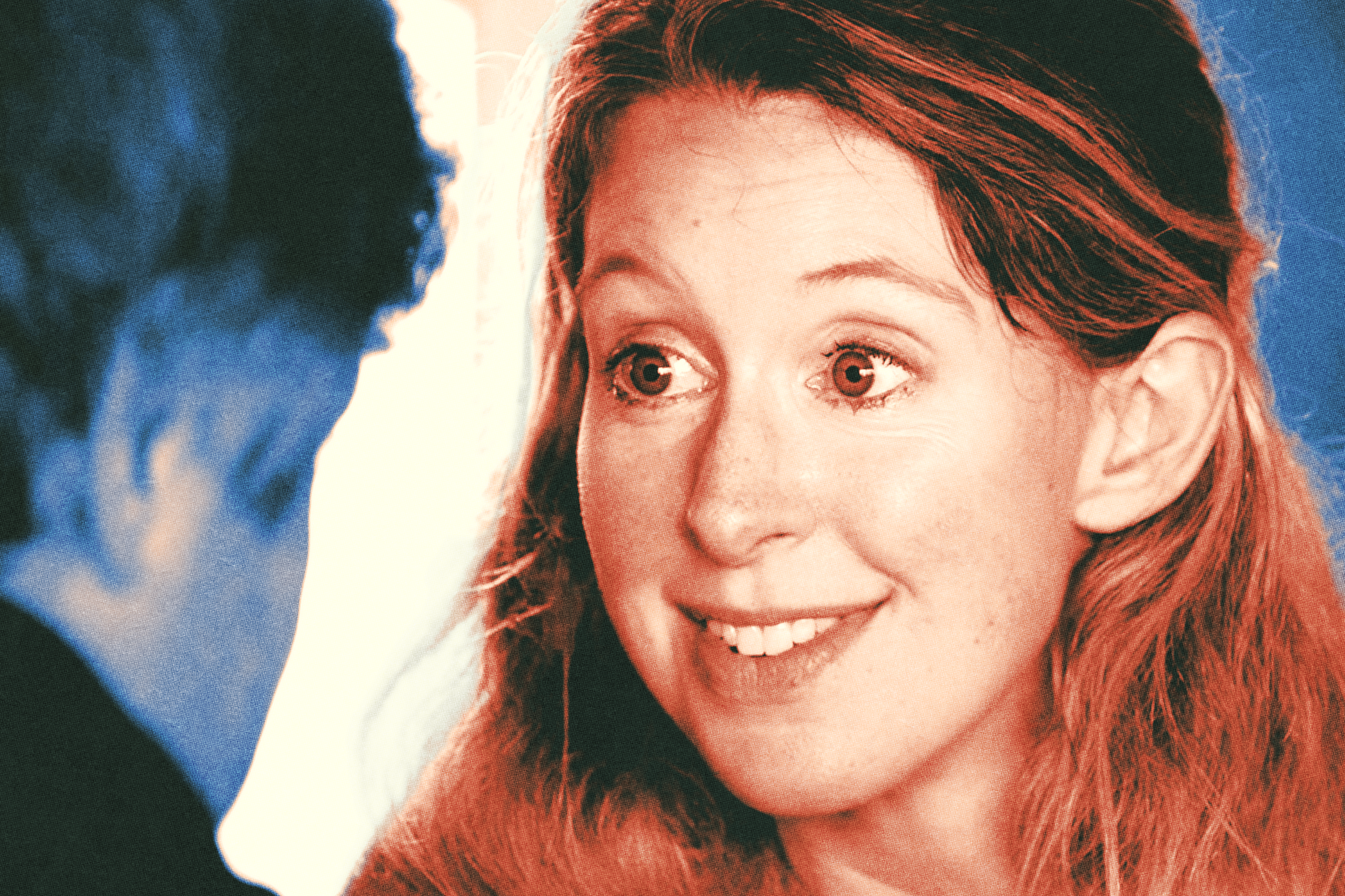 A woman with long red hair smiles warmly and looks at a person with short hair, partially seen from behind in the foreground.