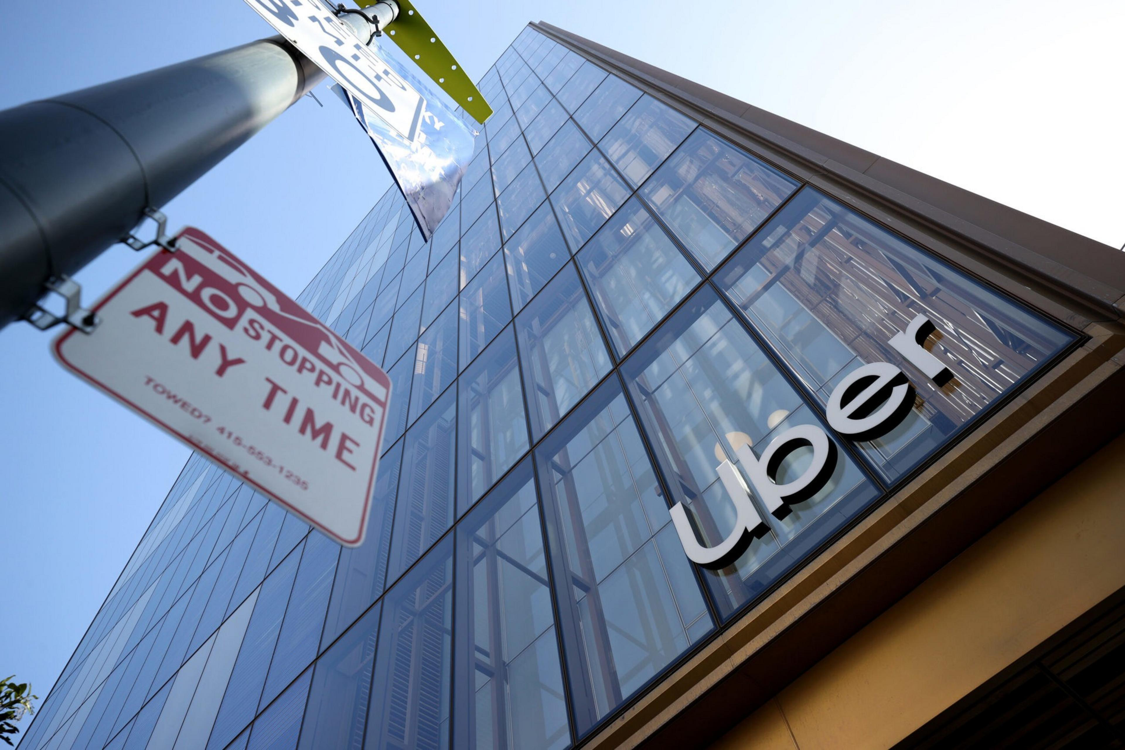 A sign posted outside a large office building is seen from below.