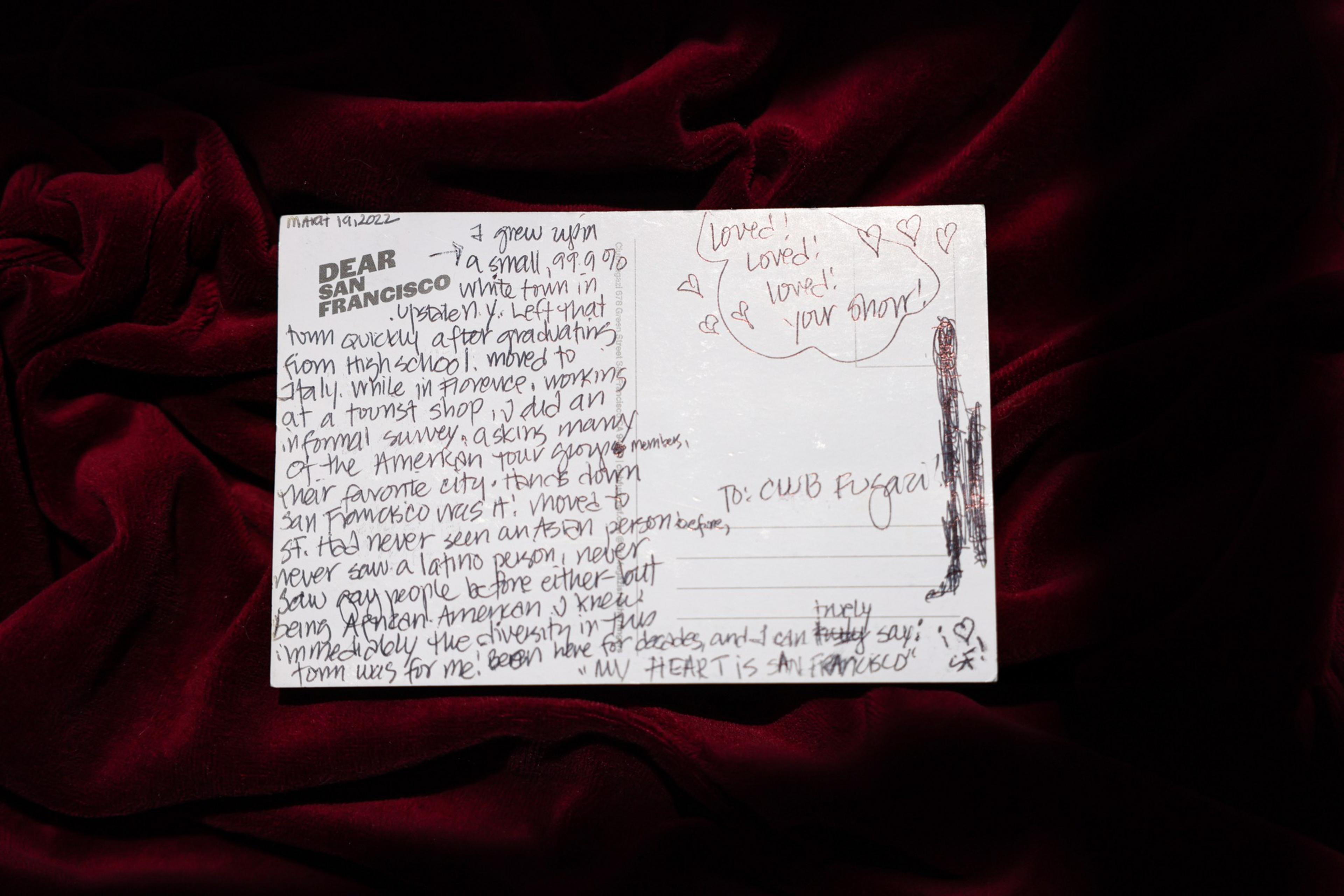 A handwritten postcard on red velvet fabric shares a personal story about growing up in a mostly white town and a deep love for San Francisco.