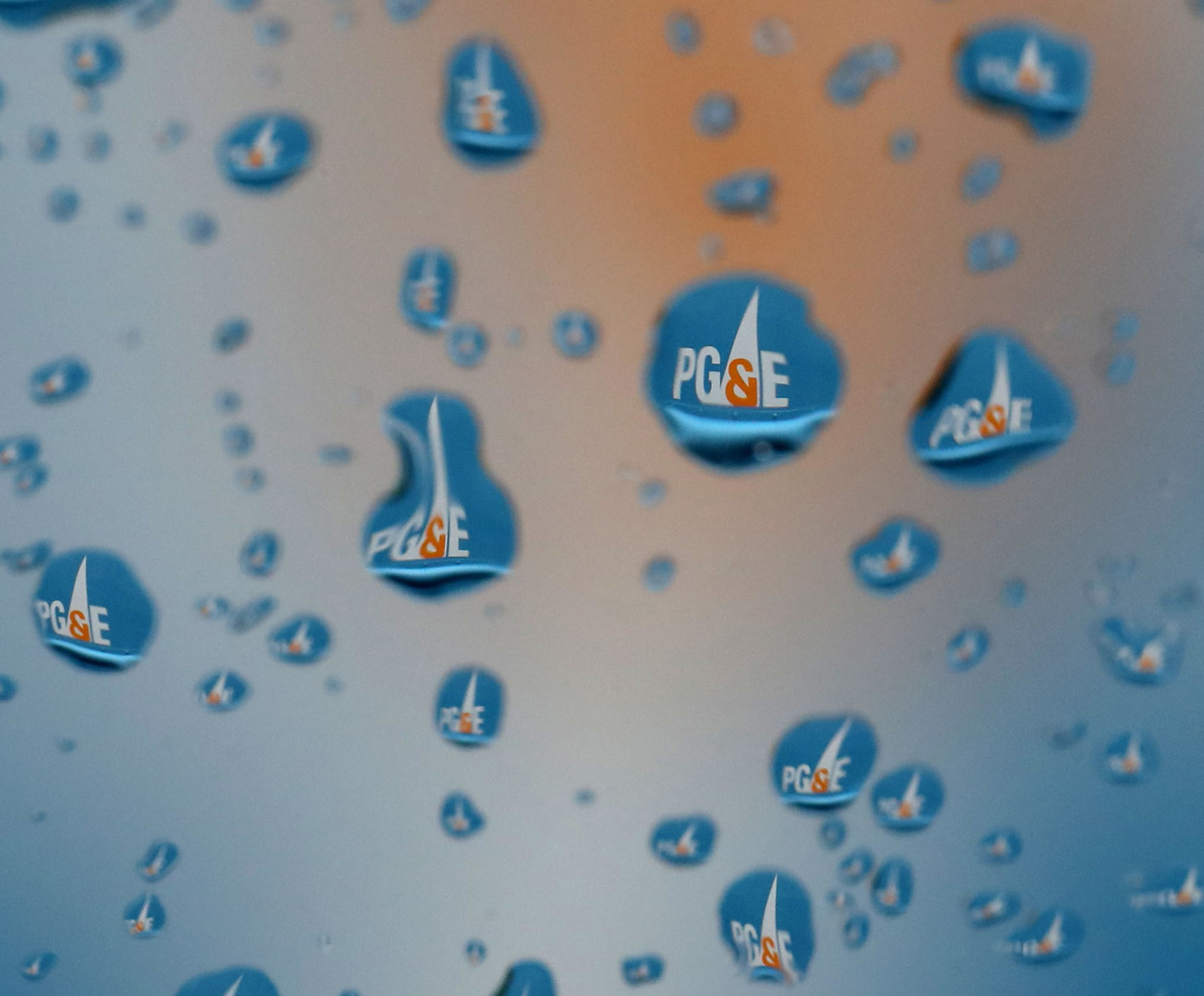 Water droplets on a surface reflecting a blue and white logo, creating a pattern of logo repetitions within each droplet.