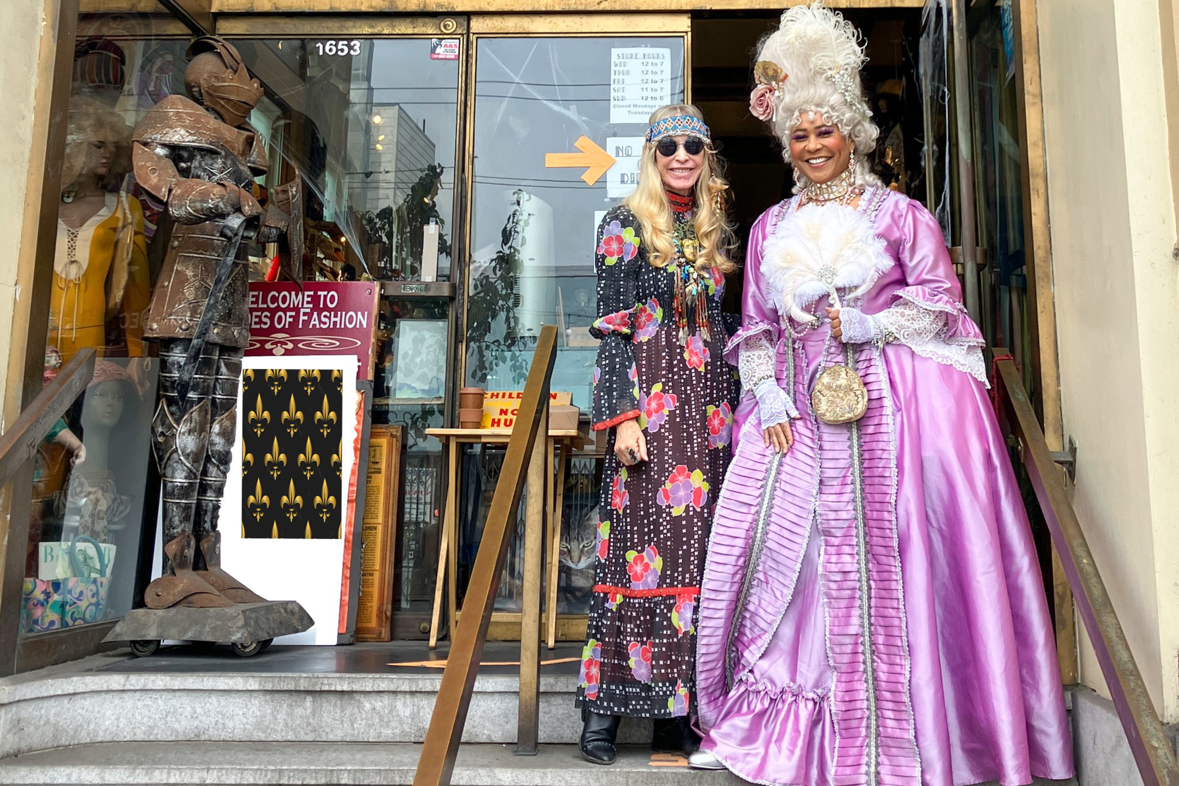 A woman in a vintage floral dress and sunglasses stands next to another woman in an elaborate pink 18th-century style gown with a feathered wig.