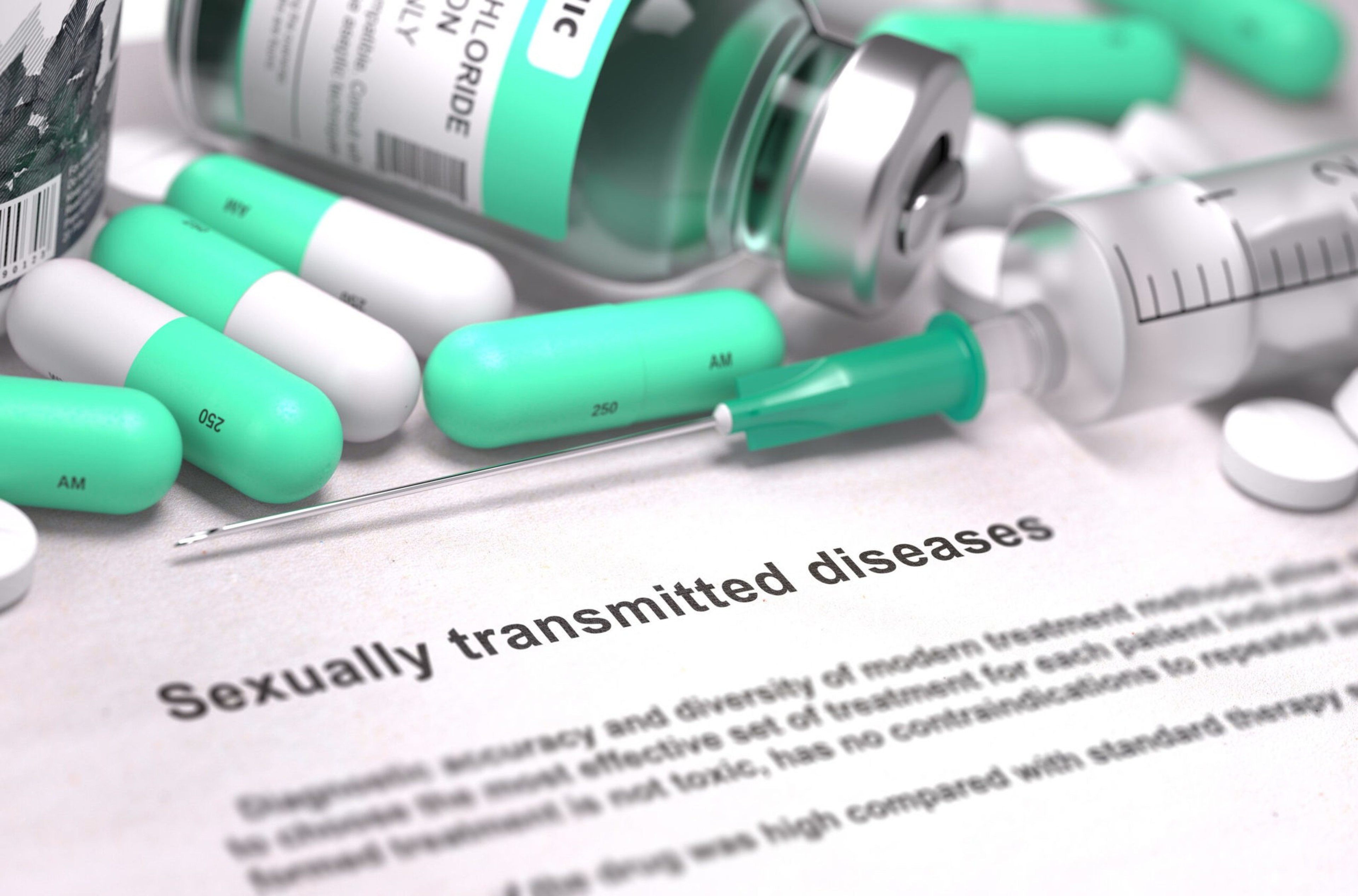 Capsules, a syringe, and medication bottles on paper titled "Sexually transmitted diseases."