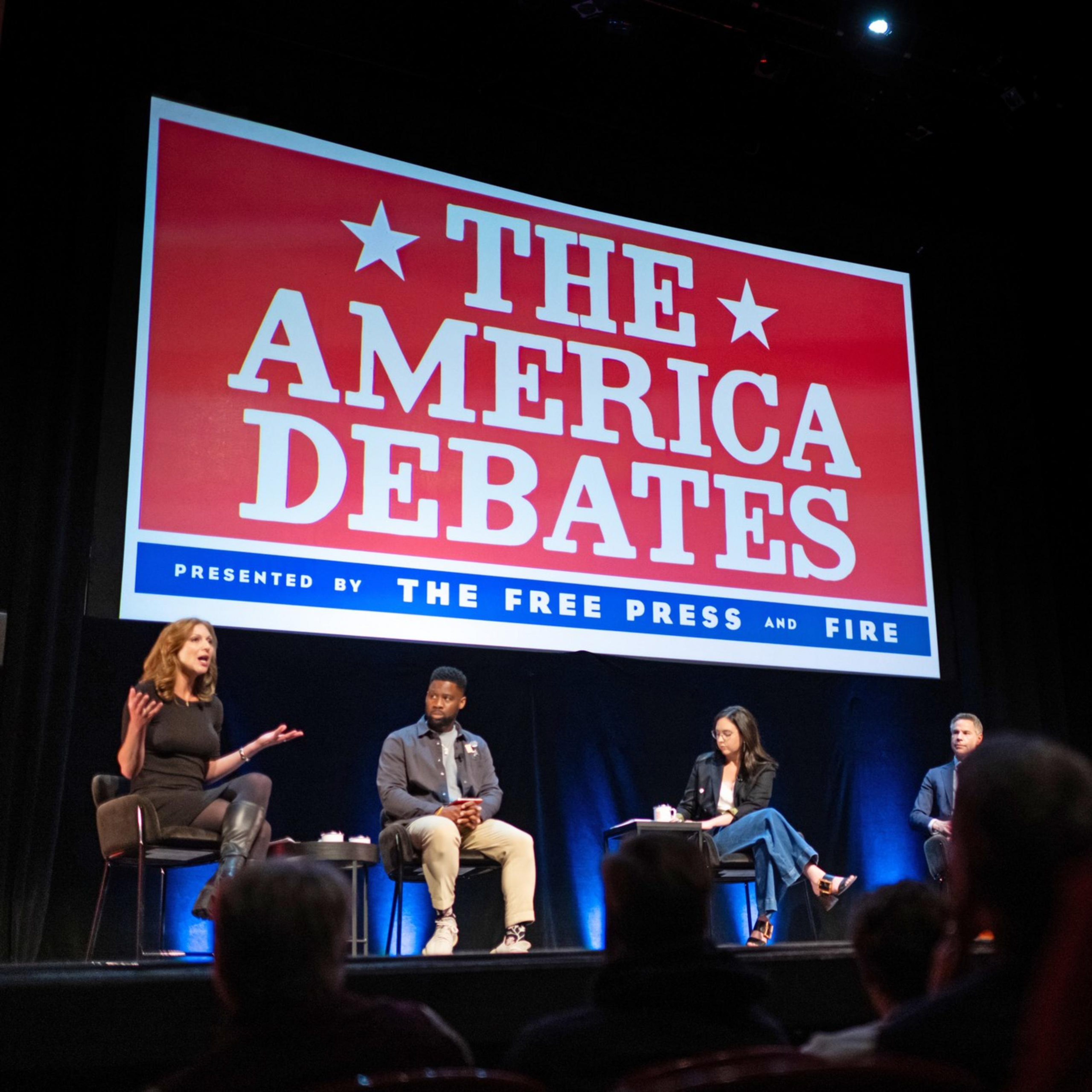 Five individuals are seated on stage under a large sign reading "The America Debates," hosted by The Free Press and FIRE, engaging in a discussion or debate.