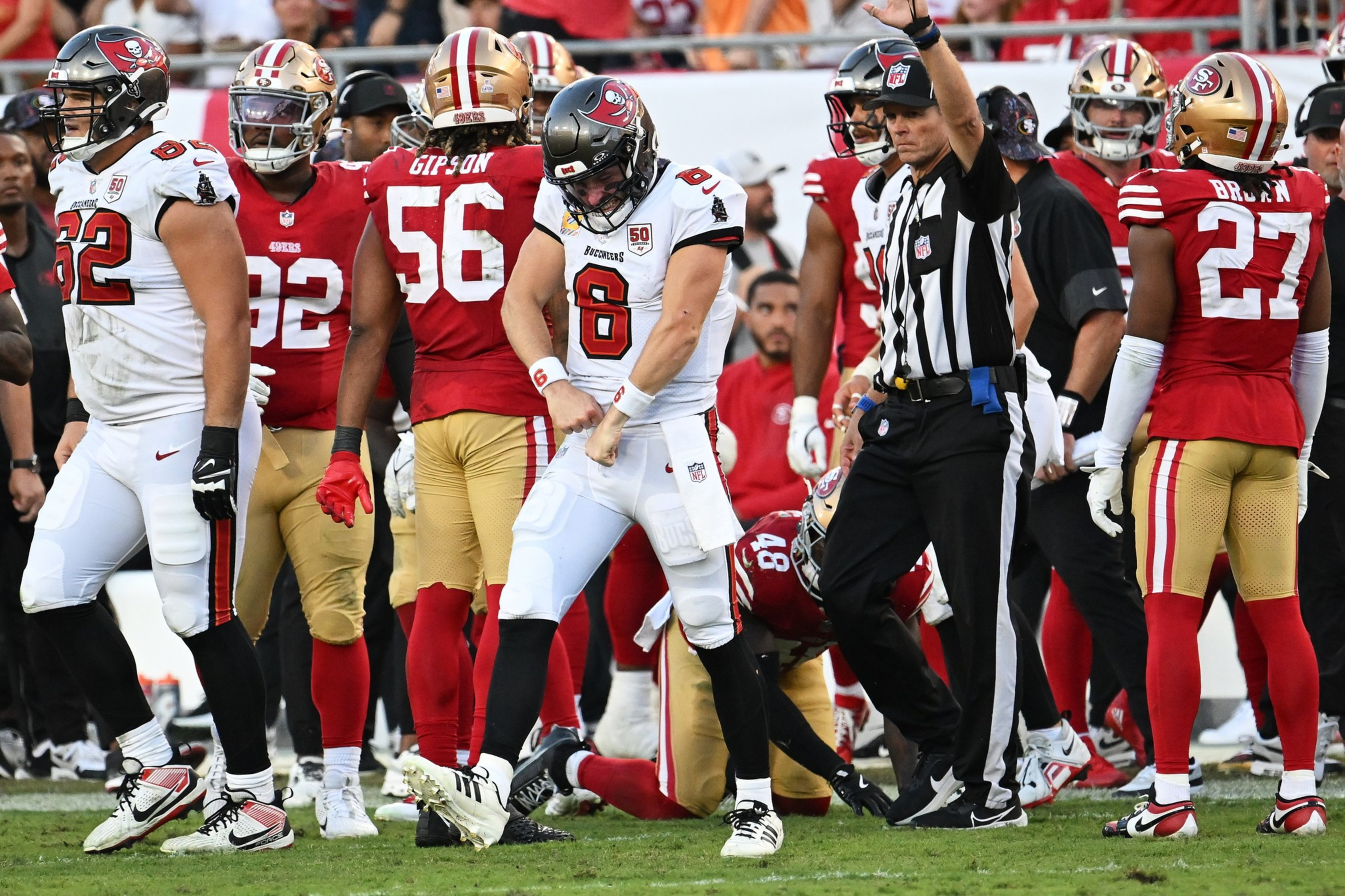 A Tampa Bay Buccaneers player celebrates while a 49ers defender lies on the ground and a referee raises his hand signaling a call.