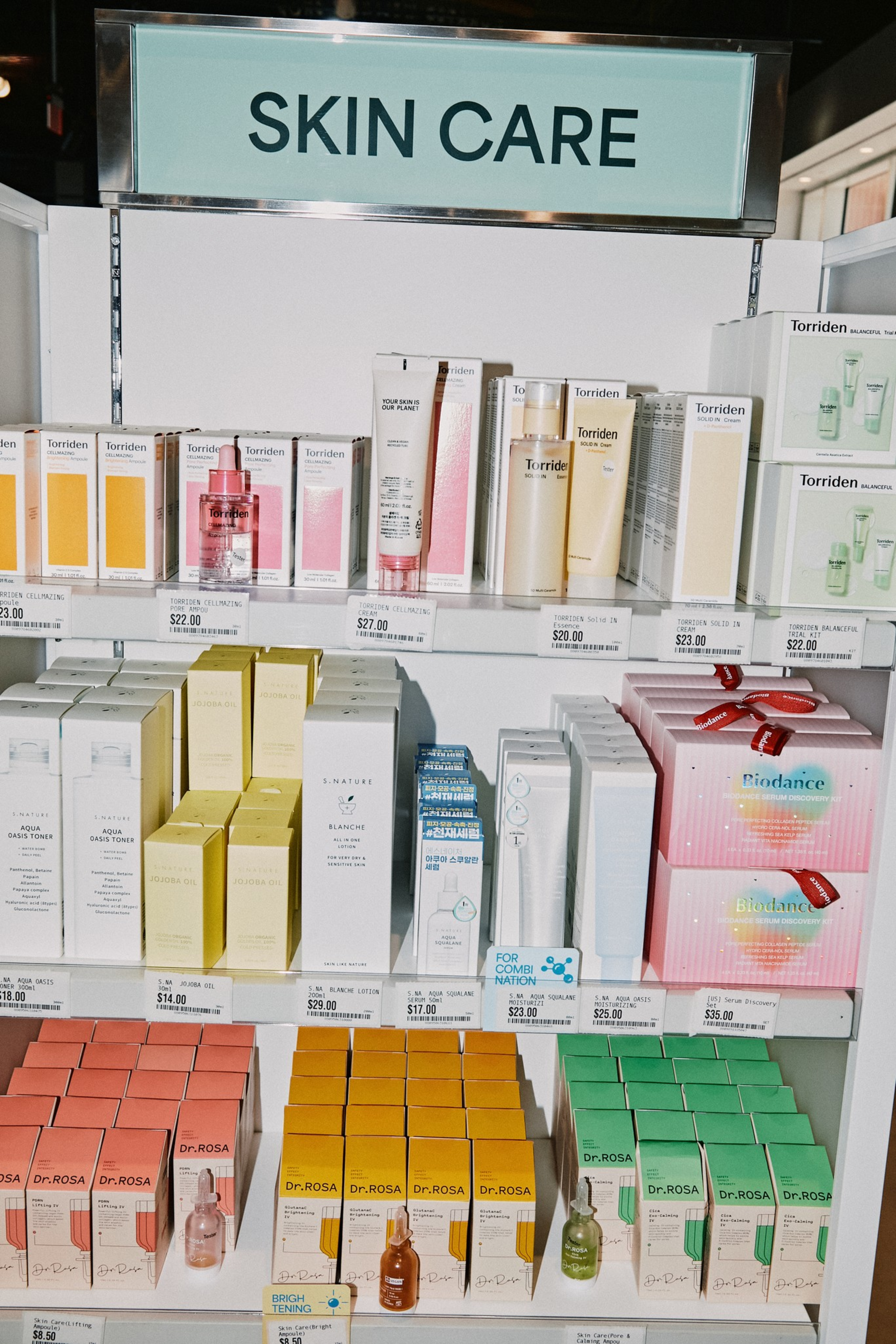 Shelves display various skin care products including serums, cleansers, and toners in colorful packaging labeled with brands like Torriden, Biodance, and Dr. Rosa.