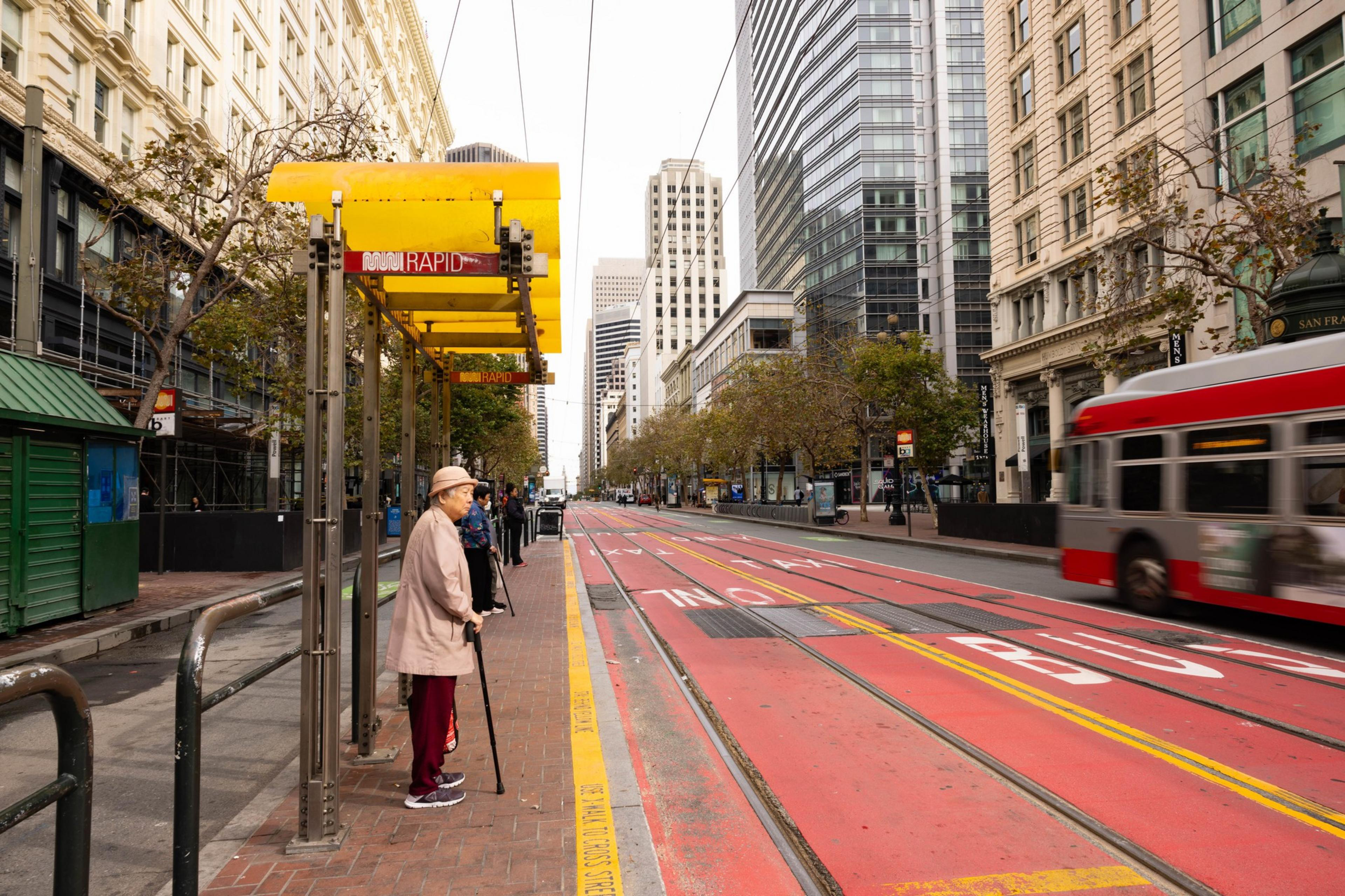 A person waits for the bus on Market St. in San Francisco.