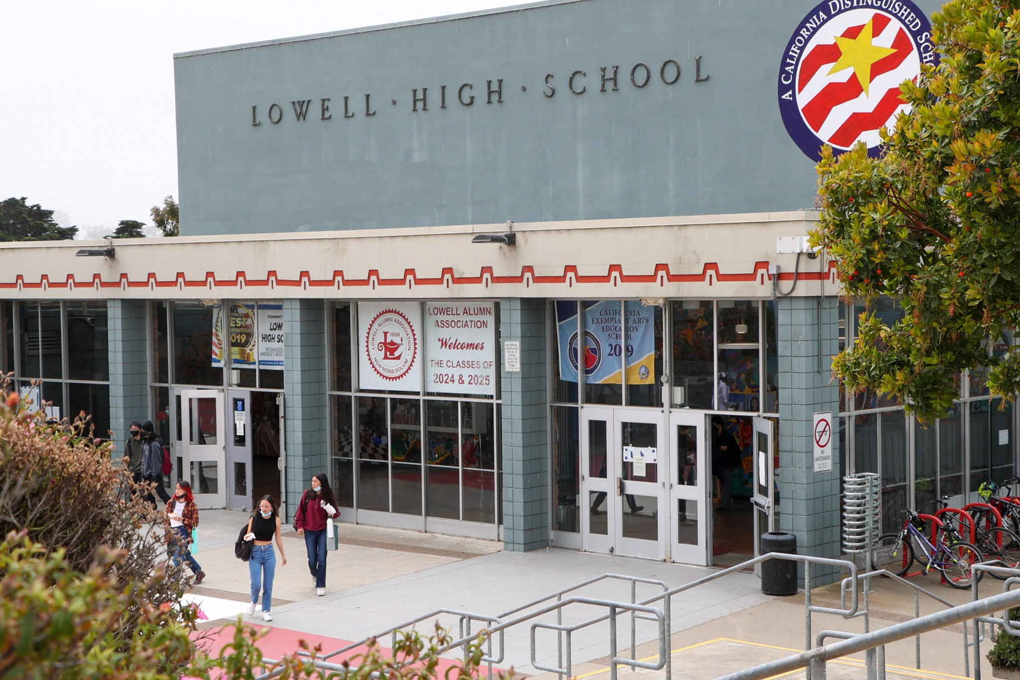Lowell High School entrance with students walking out, banners welcoming classes of 2024 and 2025, and a California Distinguished School emblem.