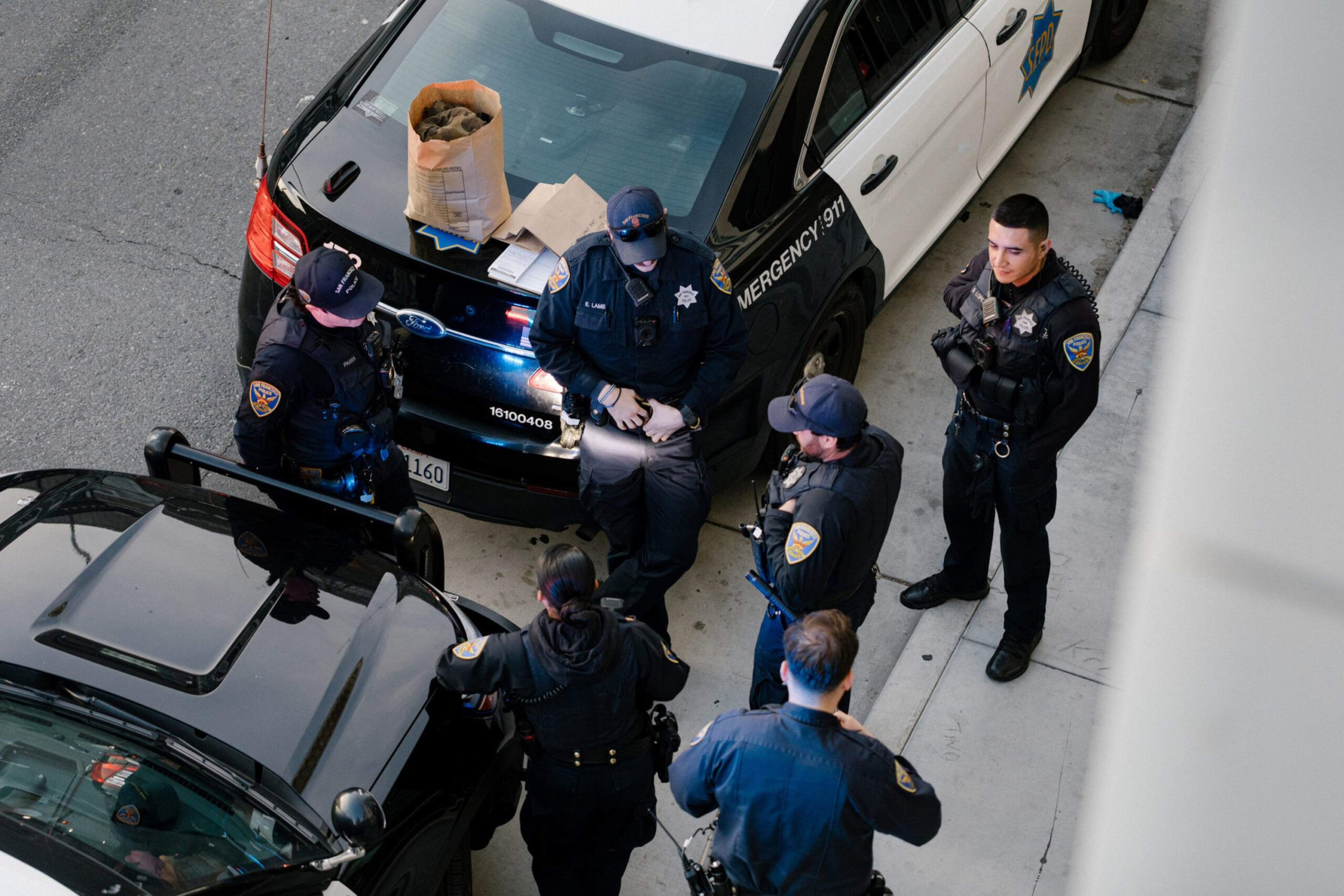 Police officers standing in a circle between two cars.