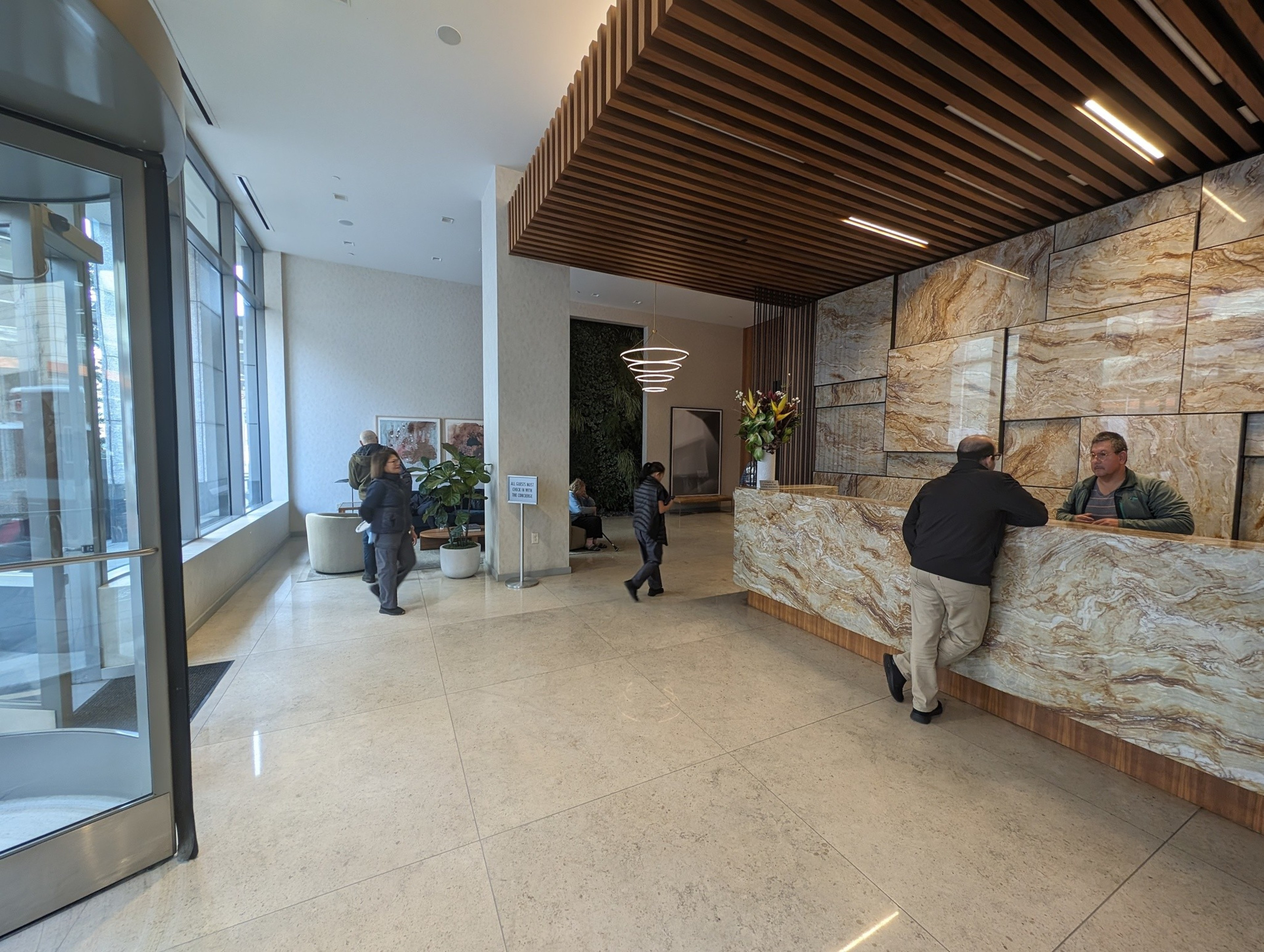 People wait in a marble floored building lobby.