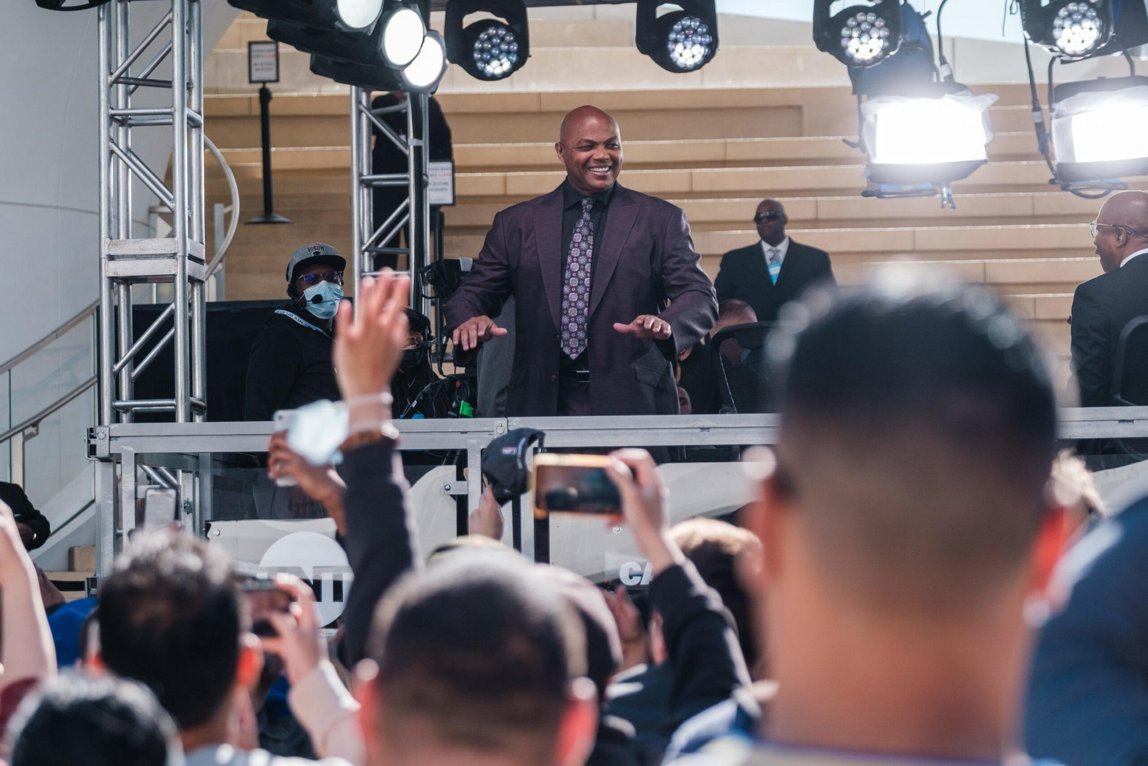 Charles Barkeley is seen on a small stage with lights above and cell phones held aloft in the crowd.