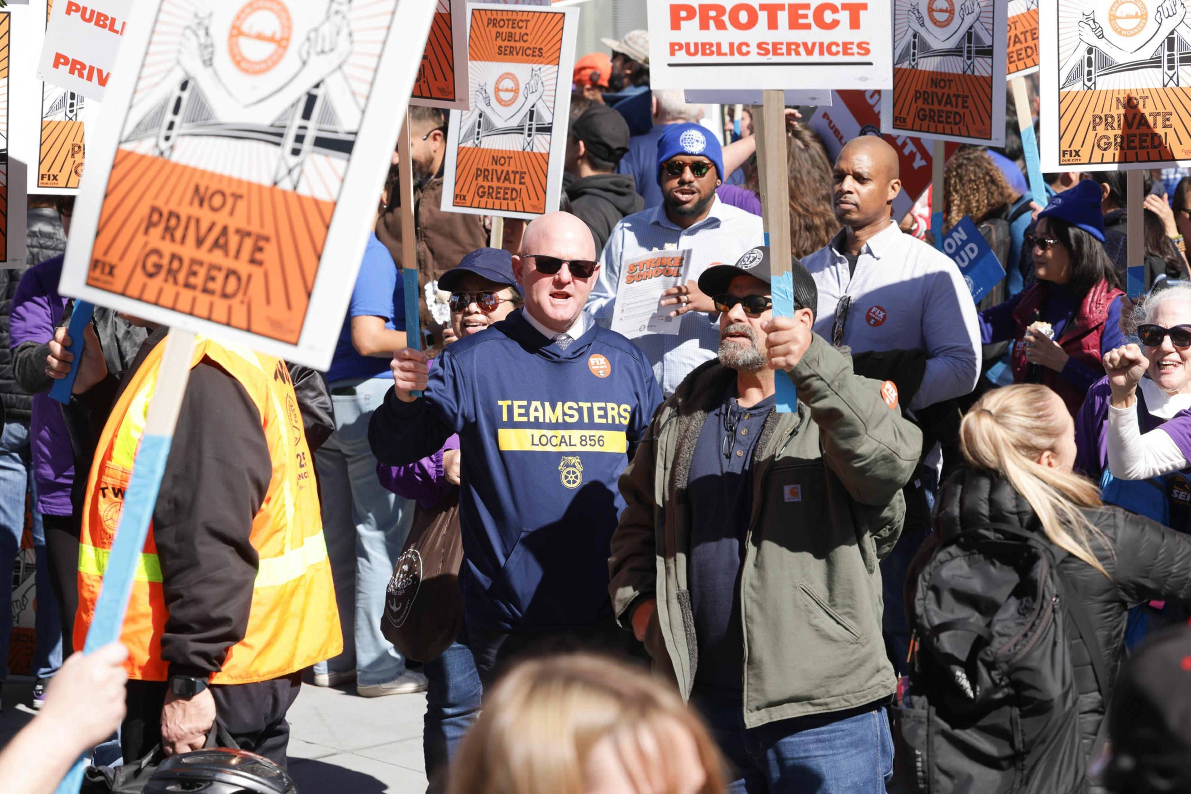 Protesters with signs rallying for public services and against privatization.