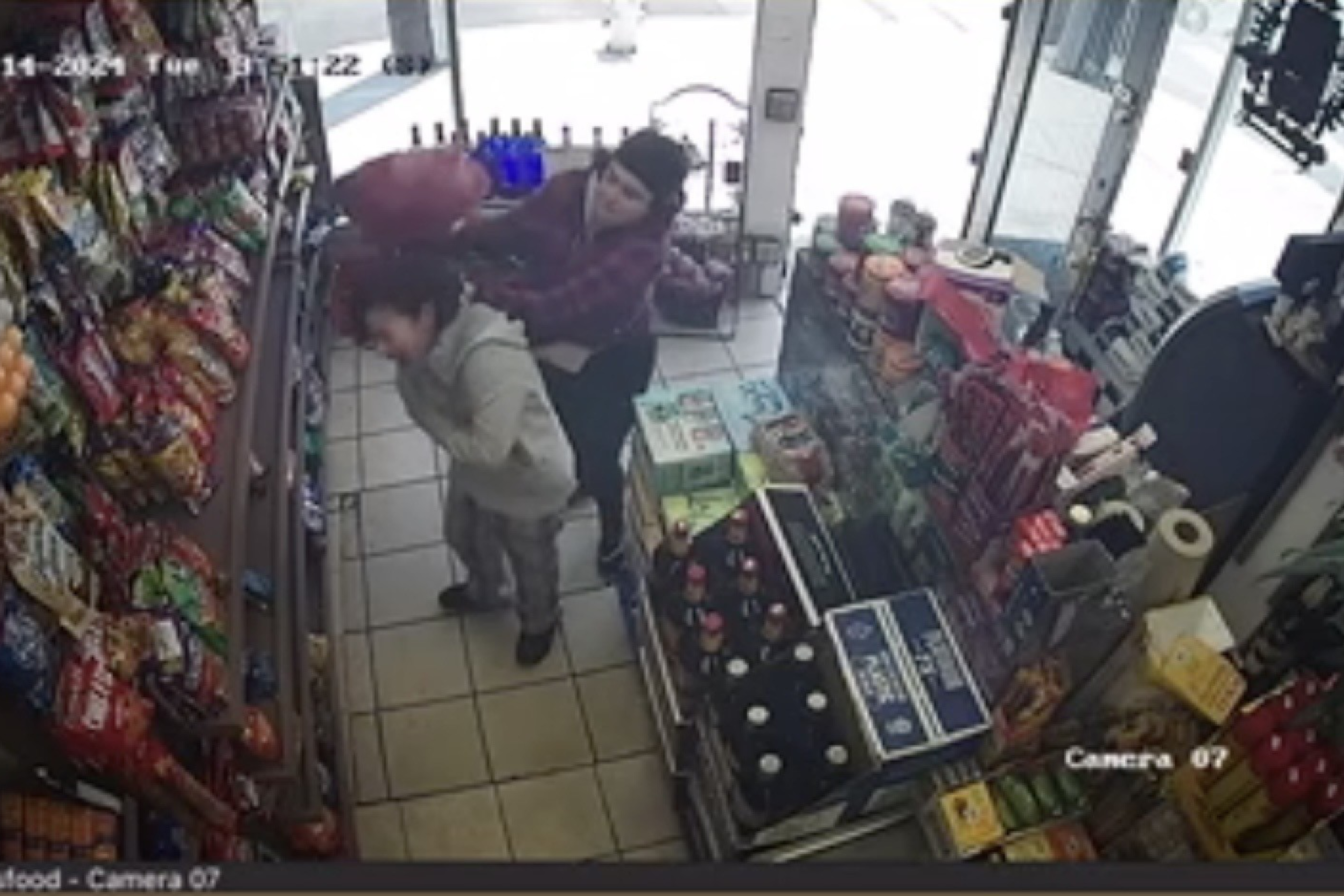 A still from surveillance video shows a woman being attacked by another woman inside a store.
