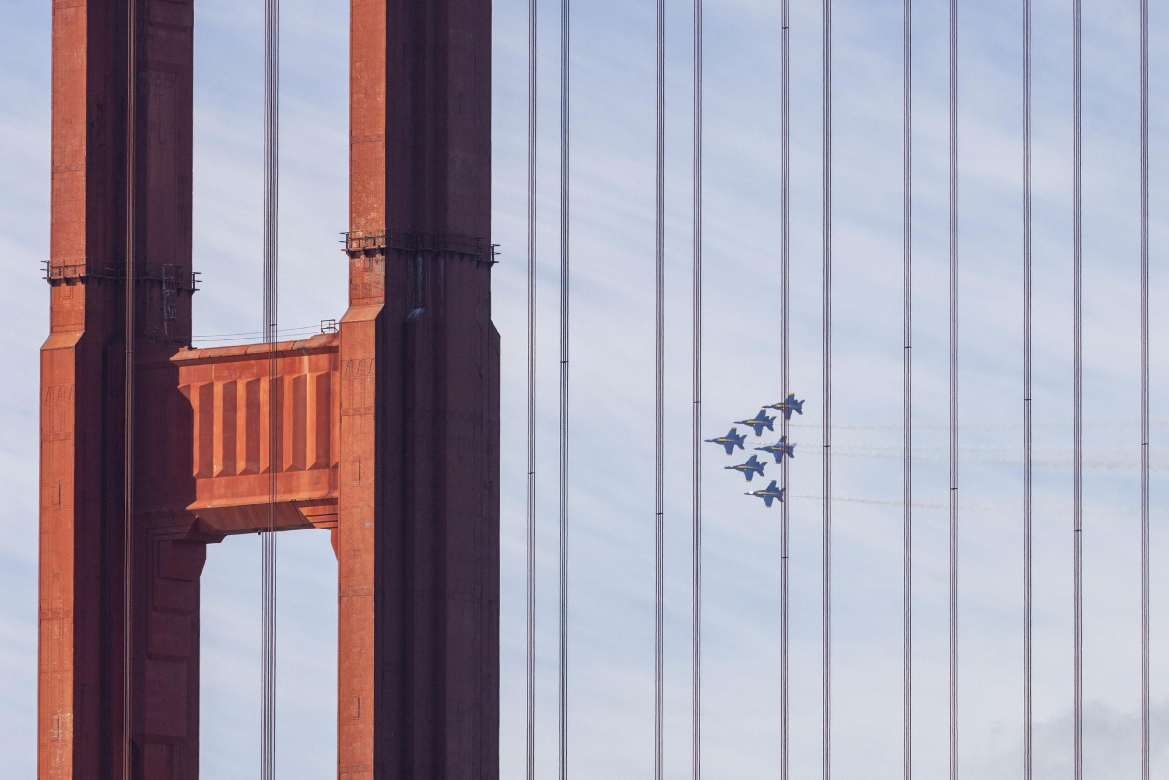 Blue jets soar behind the golden gate bridge.