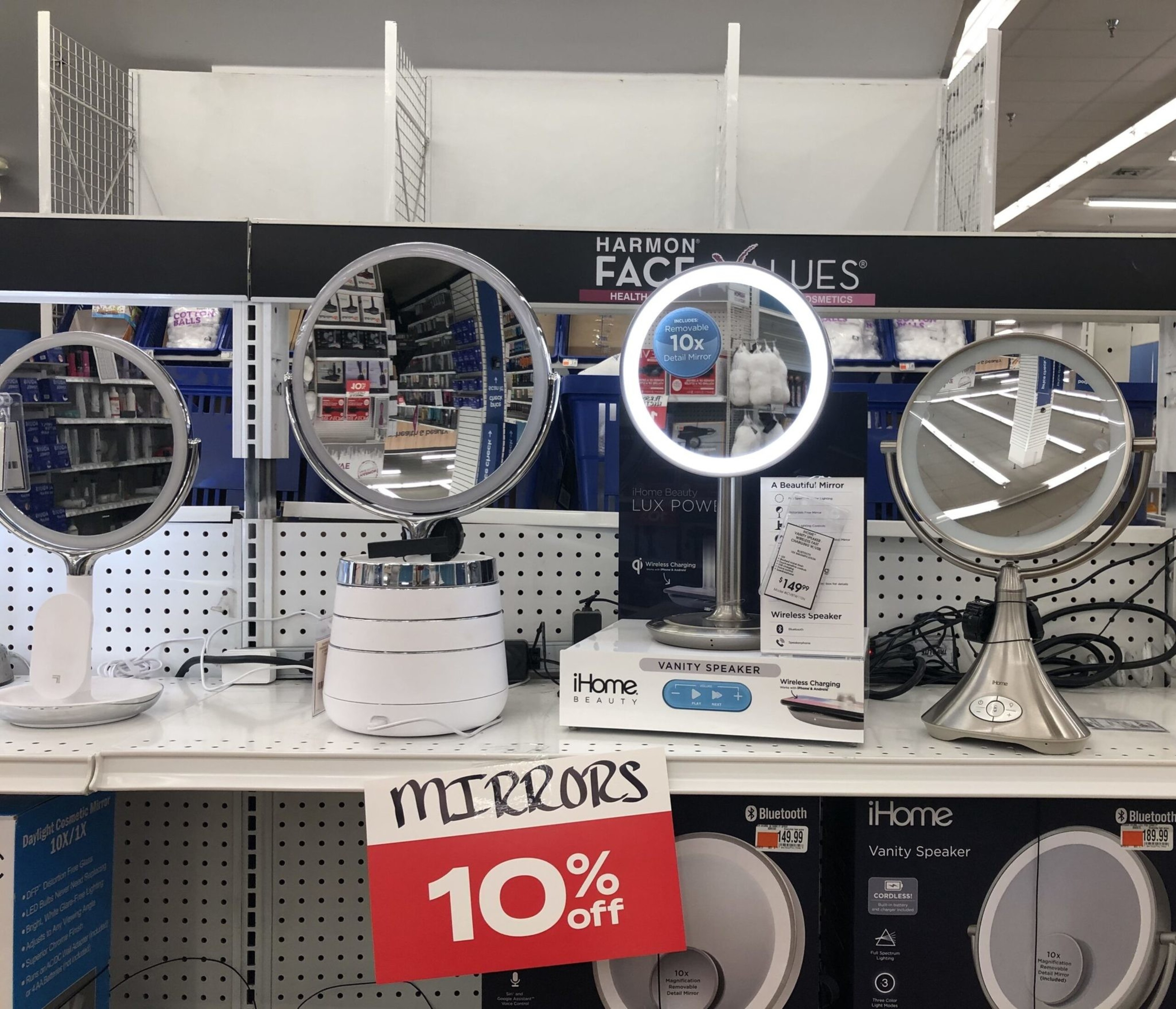 Four lighted vanity mirrors with round reflective surfaces are displayed on a store shelf, labeled with a 10% off discount sign.