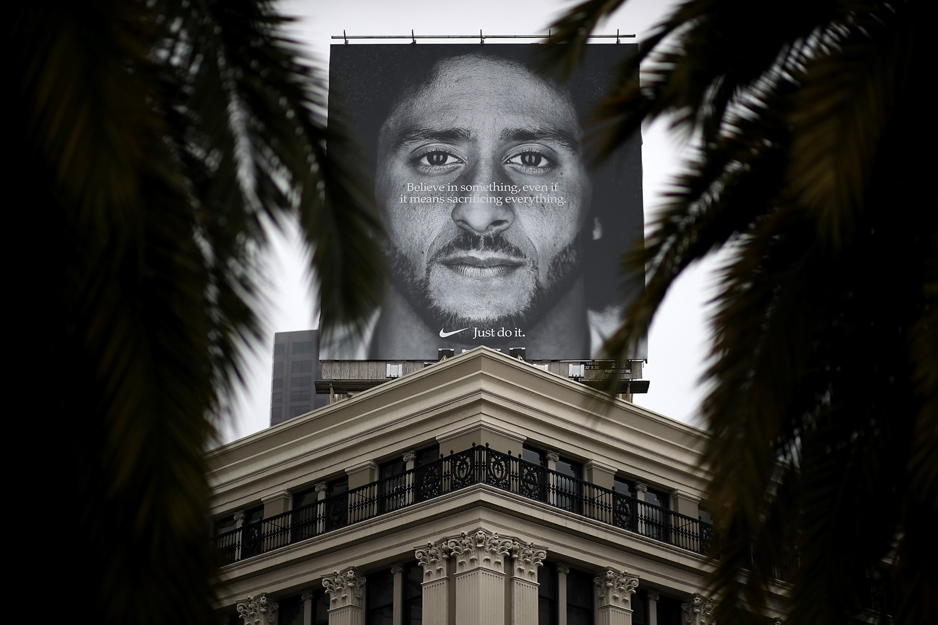A large black-and-white billboard with a close-up portrait of a man and ...
