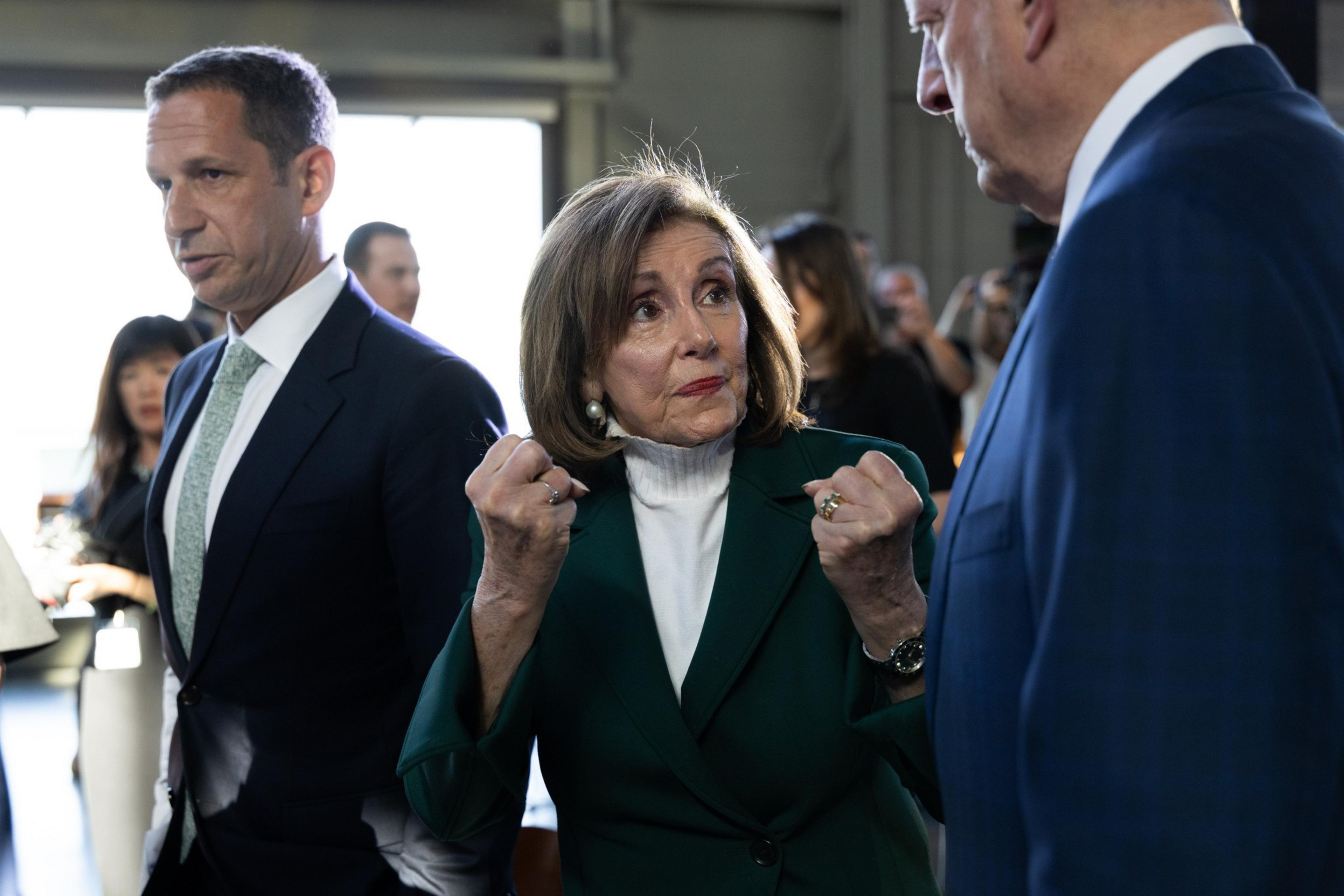 Pelosi, in front, balls two fists and holds them aloft. Lurie is to her left in a suit.